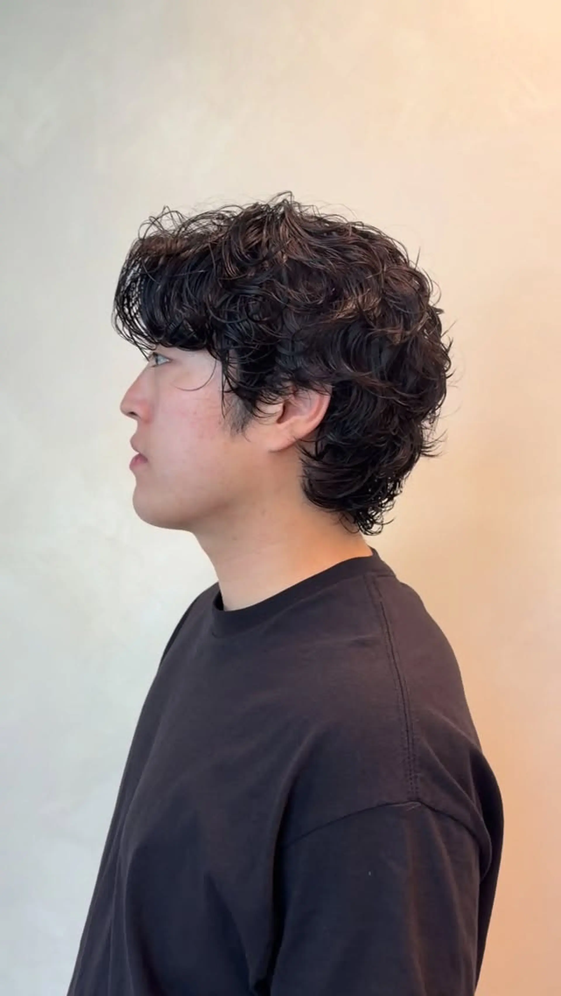 A side profile featuring a men's textured perm with natural, wavy layers and a soft wet-look finish. 1
