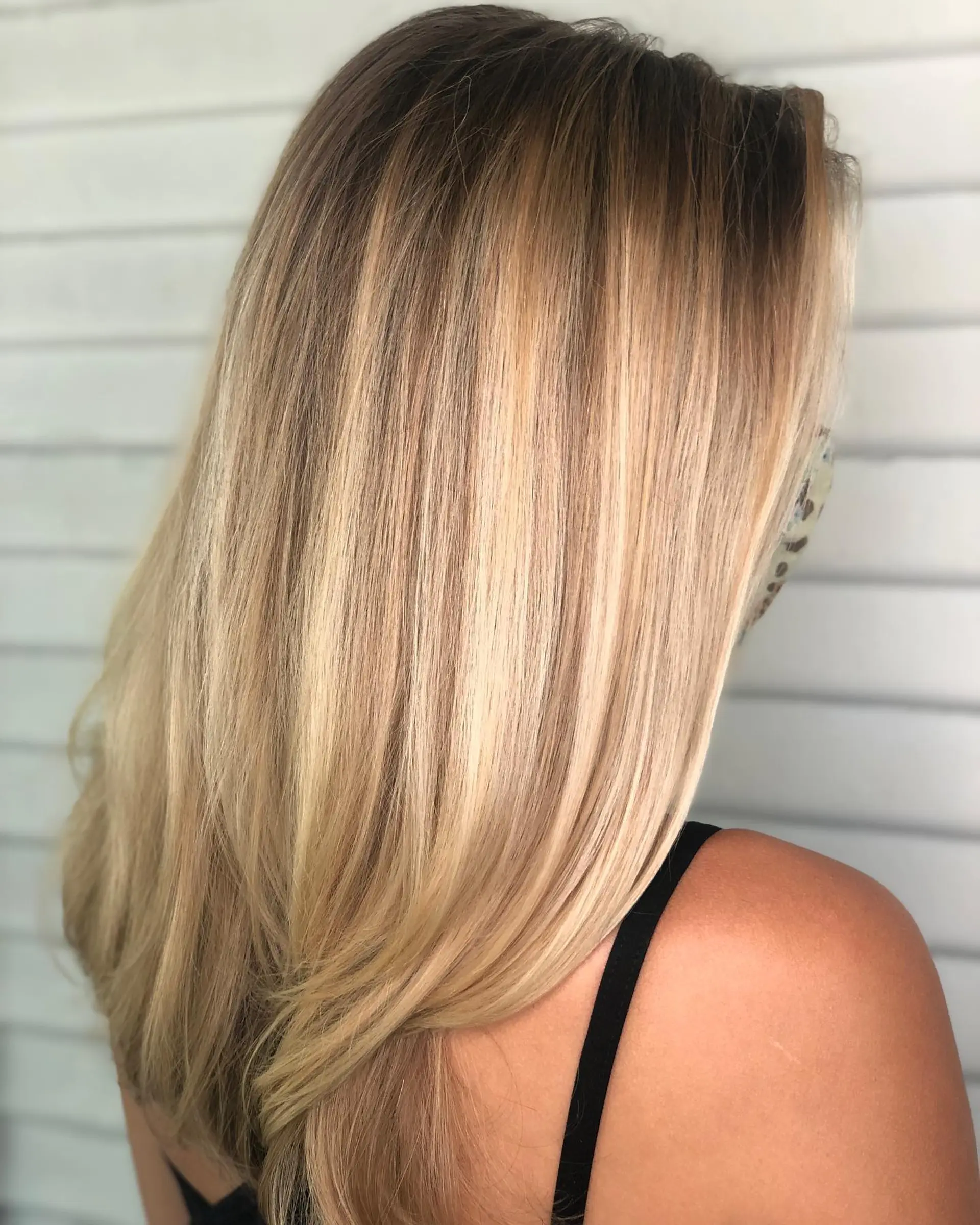 Long, smoothly styled straight hair featuring a seamless golden blonde balayage with warm dimension. 1