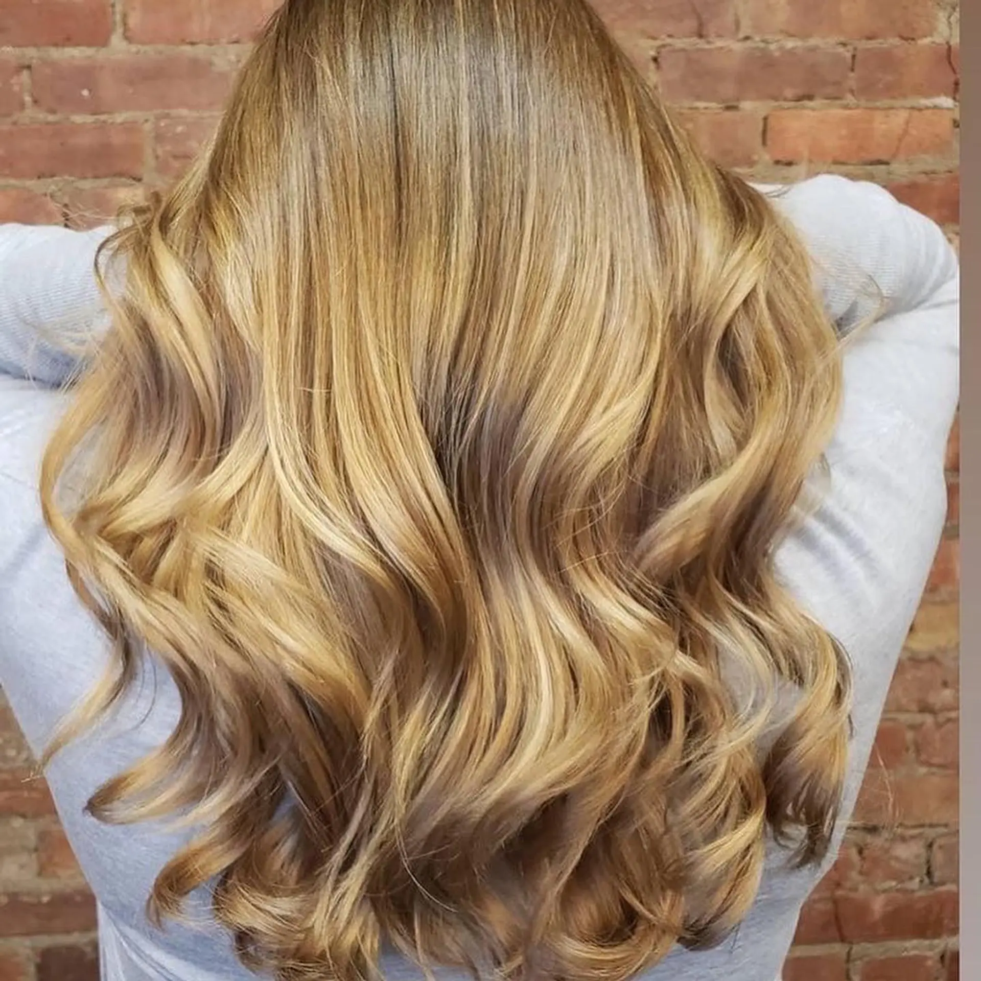 Long honey blonde dimensional balayage styled into voluminous, loose curls. 1