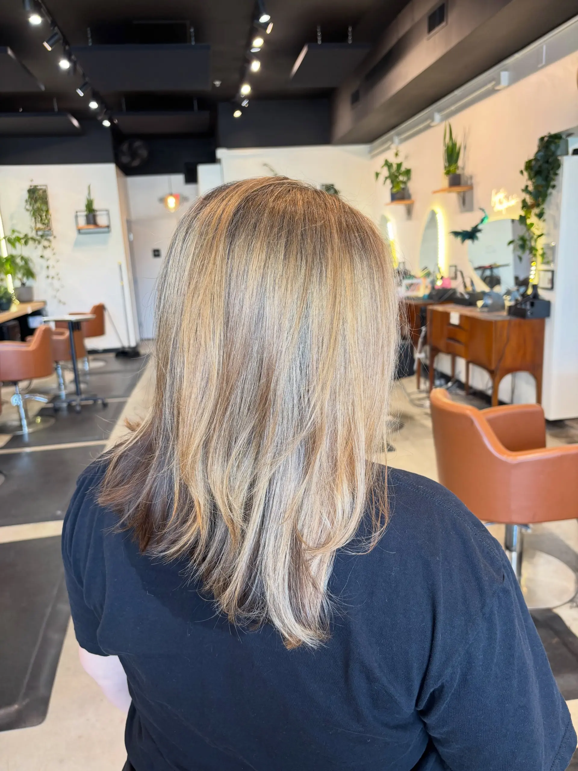 Medium-length layered haircut with dimensional honey blonde highlights blended seamlessly over a natural brown base, finished with a smooth blowout. 1