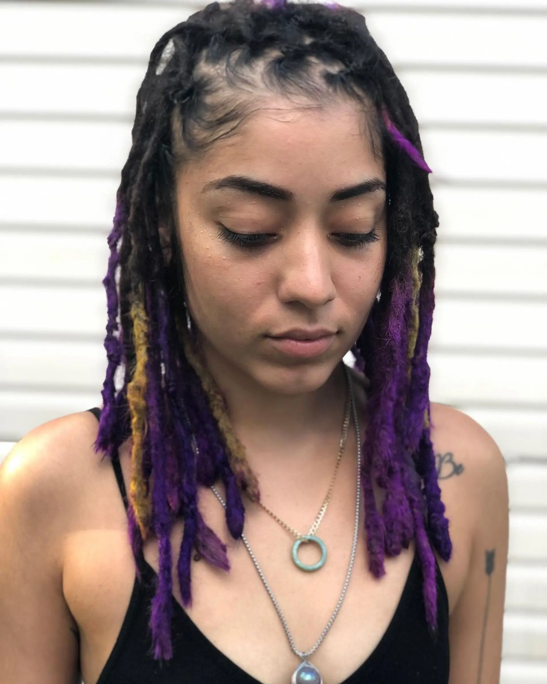 Vivid, medium-length dreadlocks with an electric purple and bright yellow ombre effect, starting from a curly texture. 1