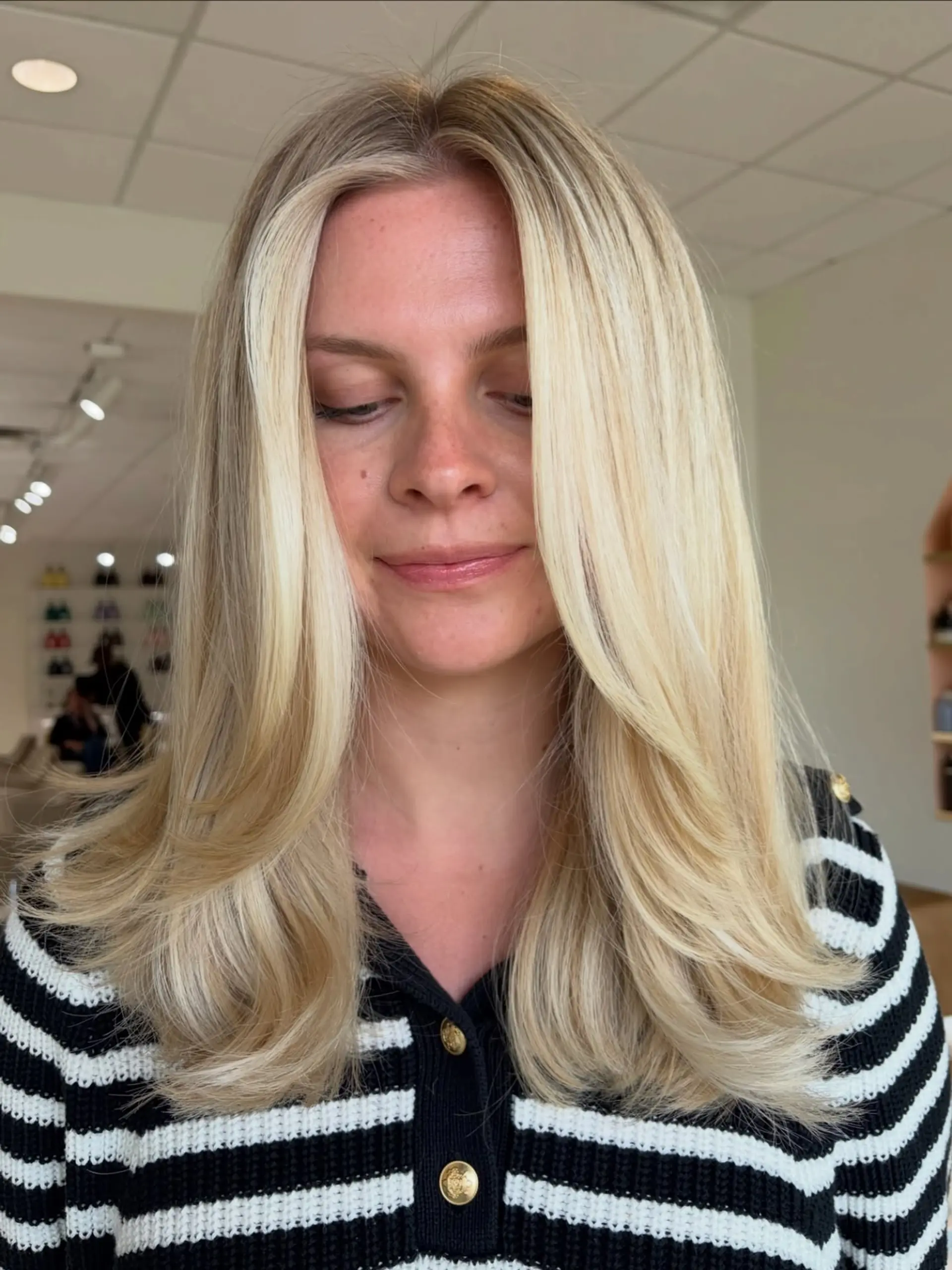 Luminous bright blonde hair cut with face-framing layers and styled into a voluminous, smooth blowout with soft curled ends. 1