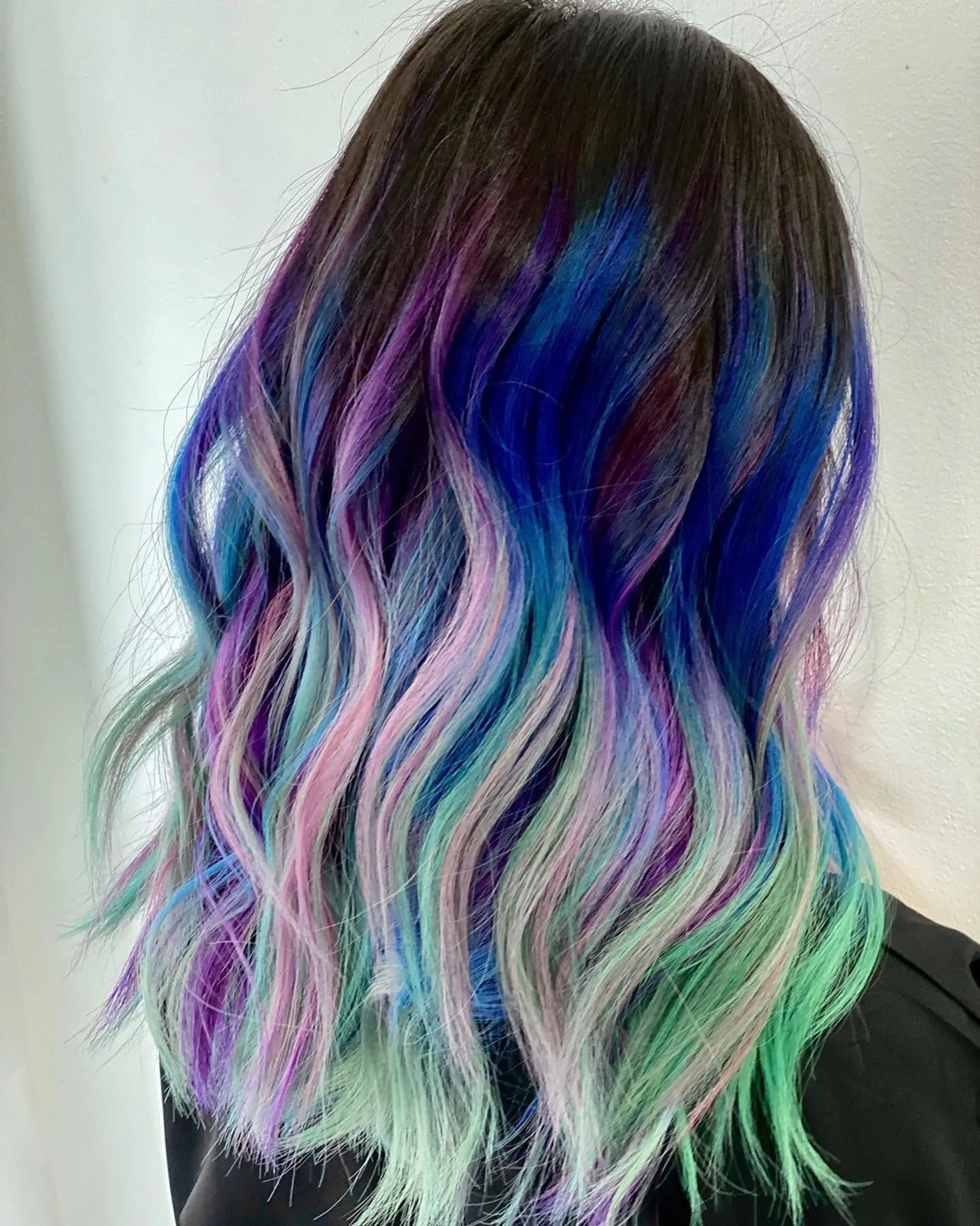 Long, wavy hair in a multi-tonal ombre with colors blue, purple, pink, teal, and light green.