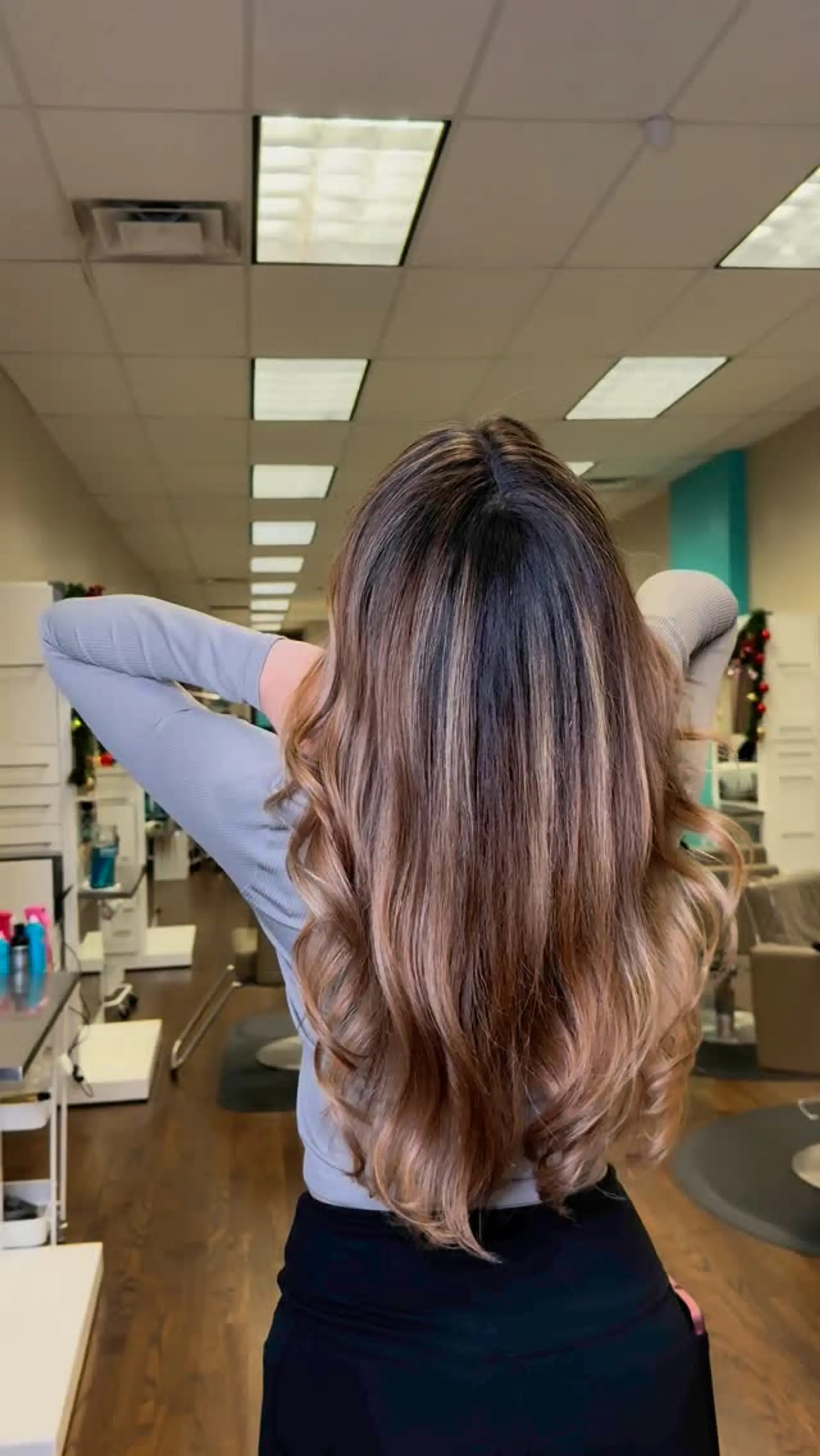 Long brunette hair styled with soft, voluminous curls featuring a warm caramel balayage gradient. 1