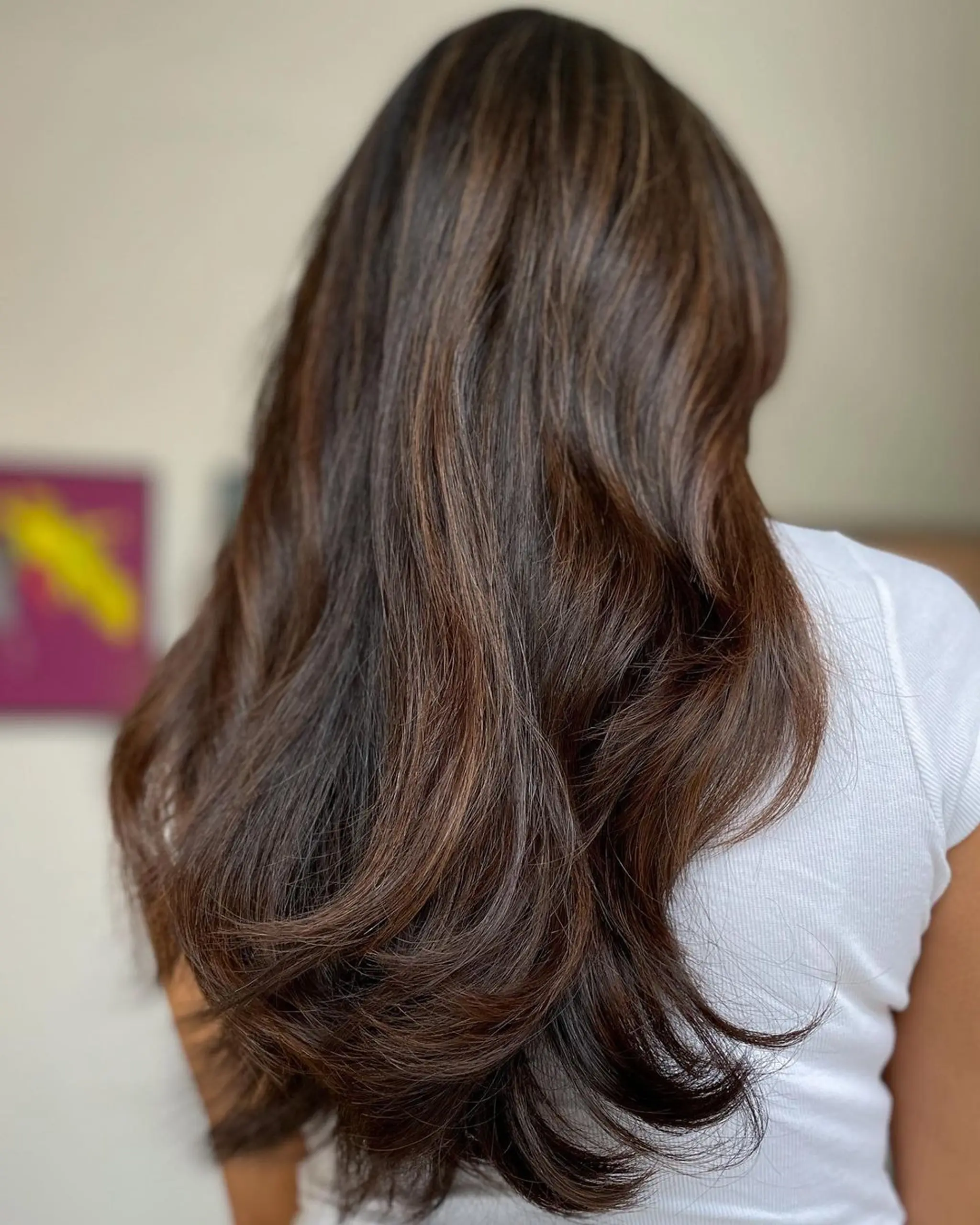 Very long, voluminous, and wavy dark brown hair with subtle highlights, featuring layered depths and natural luster.