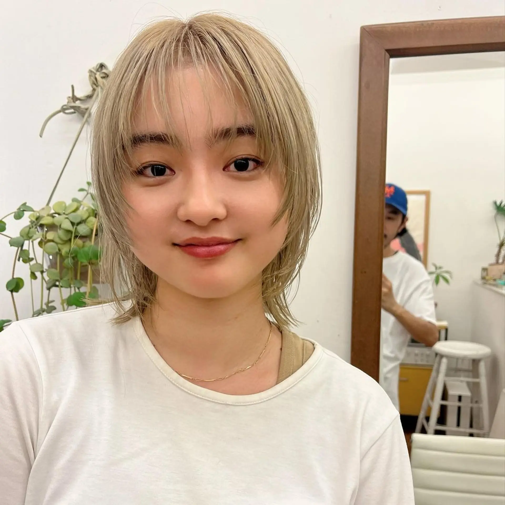 A short, straight blonde hairstyle with platinum highlights, featuring wispy bangs and feathered layers for a textured and dynamic appearance. 1