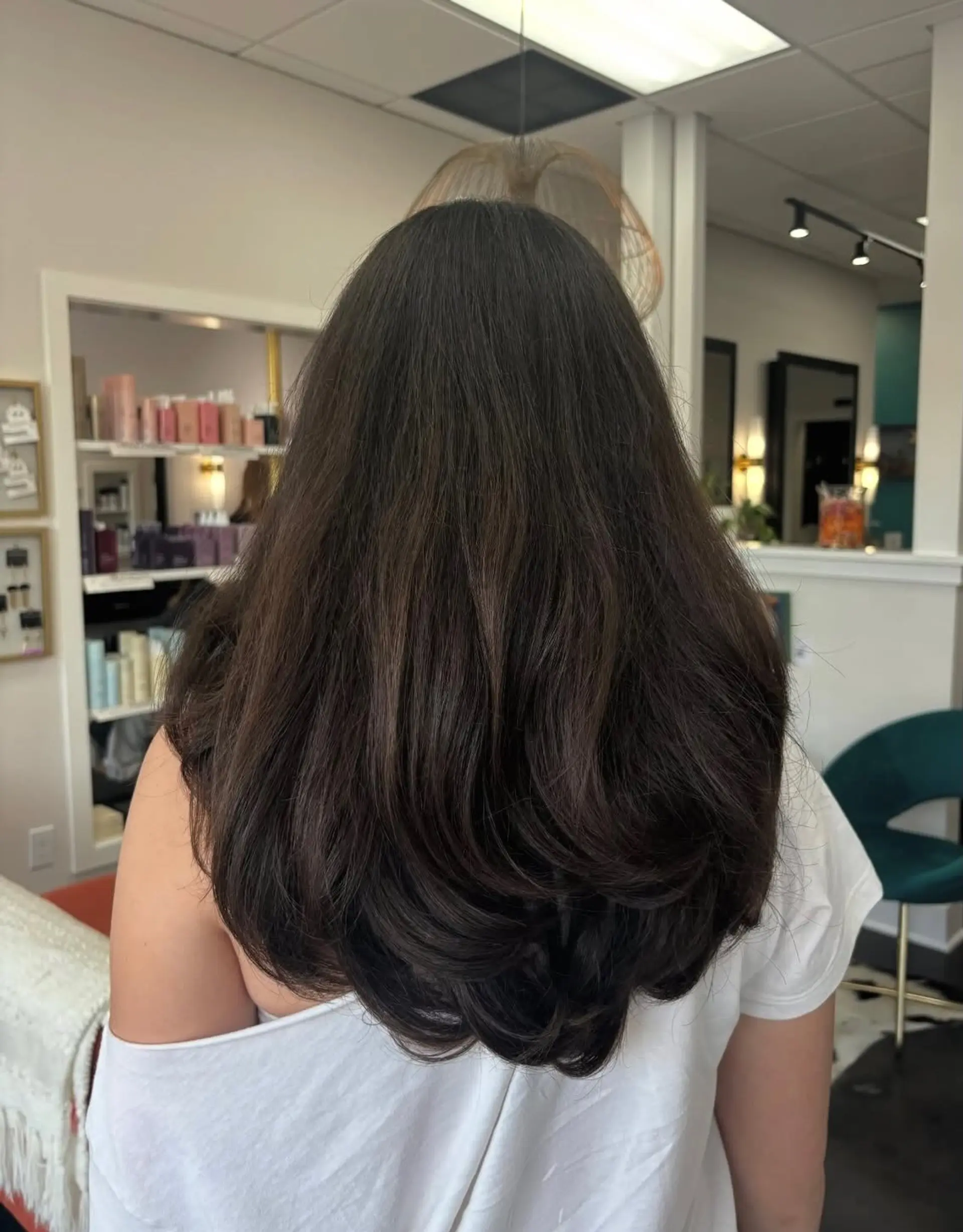 Thick, long dark brown hair styled with round-brushed layers creating bouncy, voluminous curled-under ends. 1
