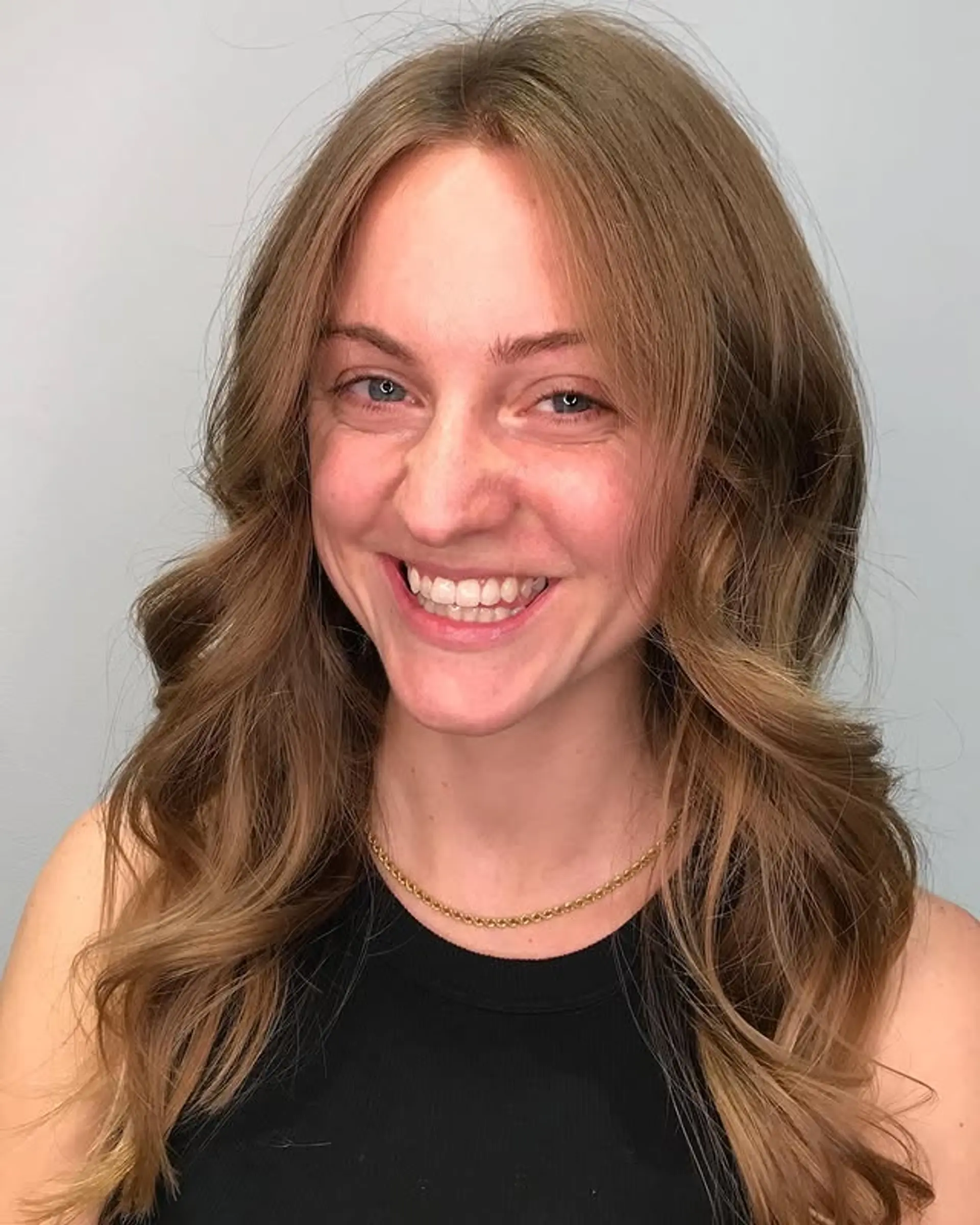 Long, wavy hair with layered cuts and face-framing layers, styled with loose, natural waves and subtle curtain bangs. 1