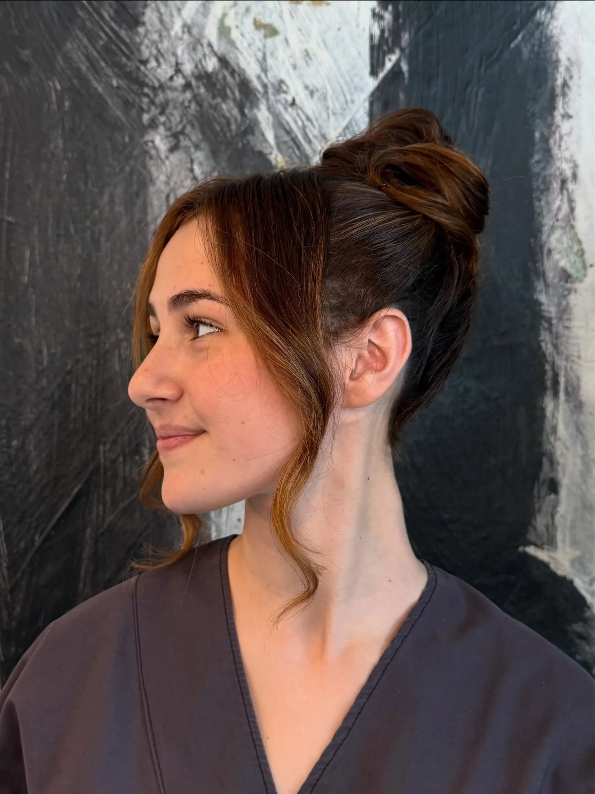 An elegant high bun updo with softly curled, face-framing tendrils. 1