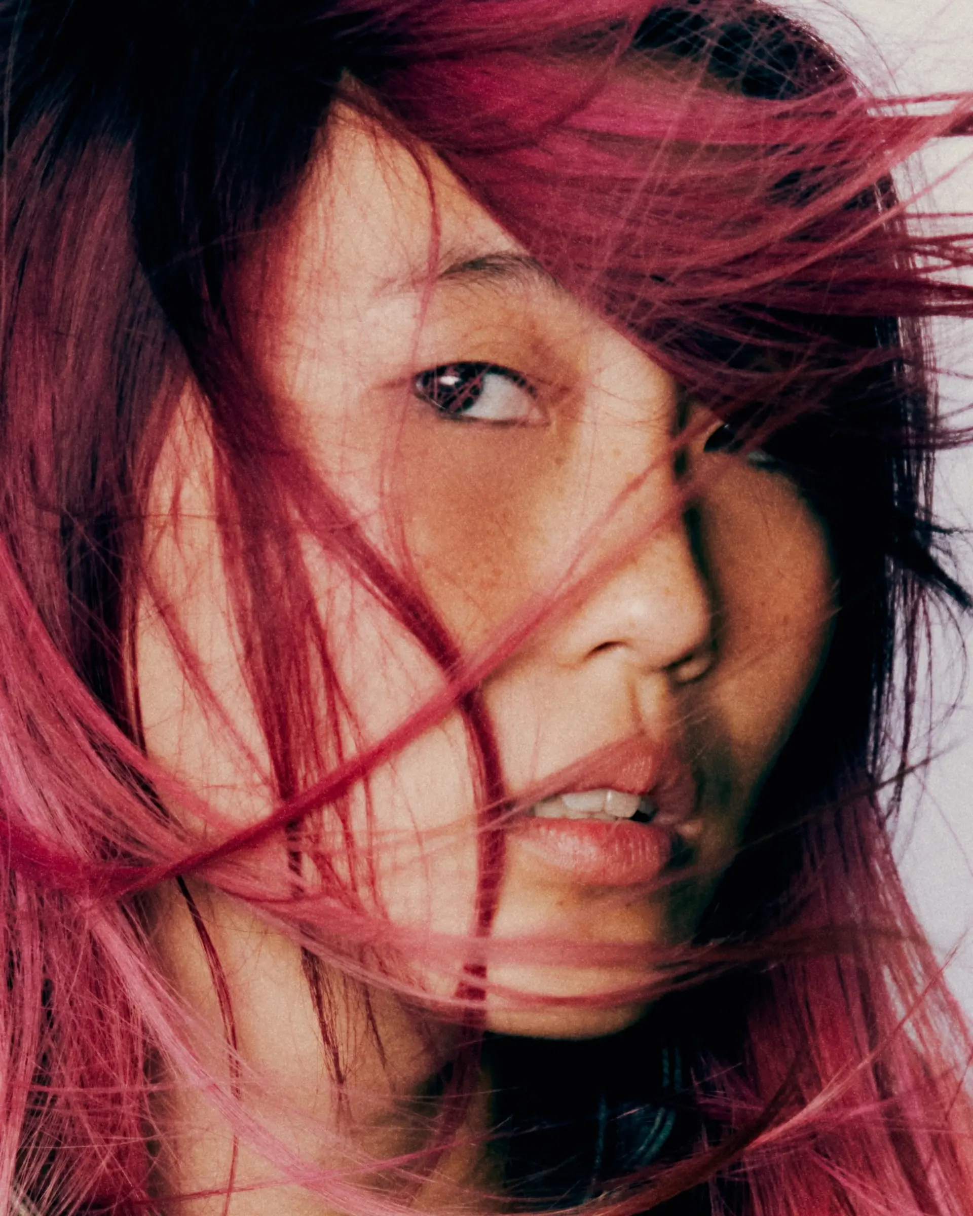 Vibrant cyber pink straight hair styled with dynamic windblown motion across the face. 1