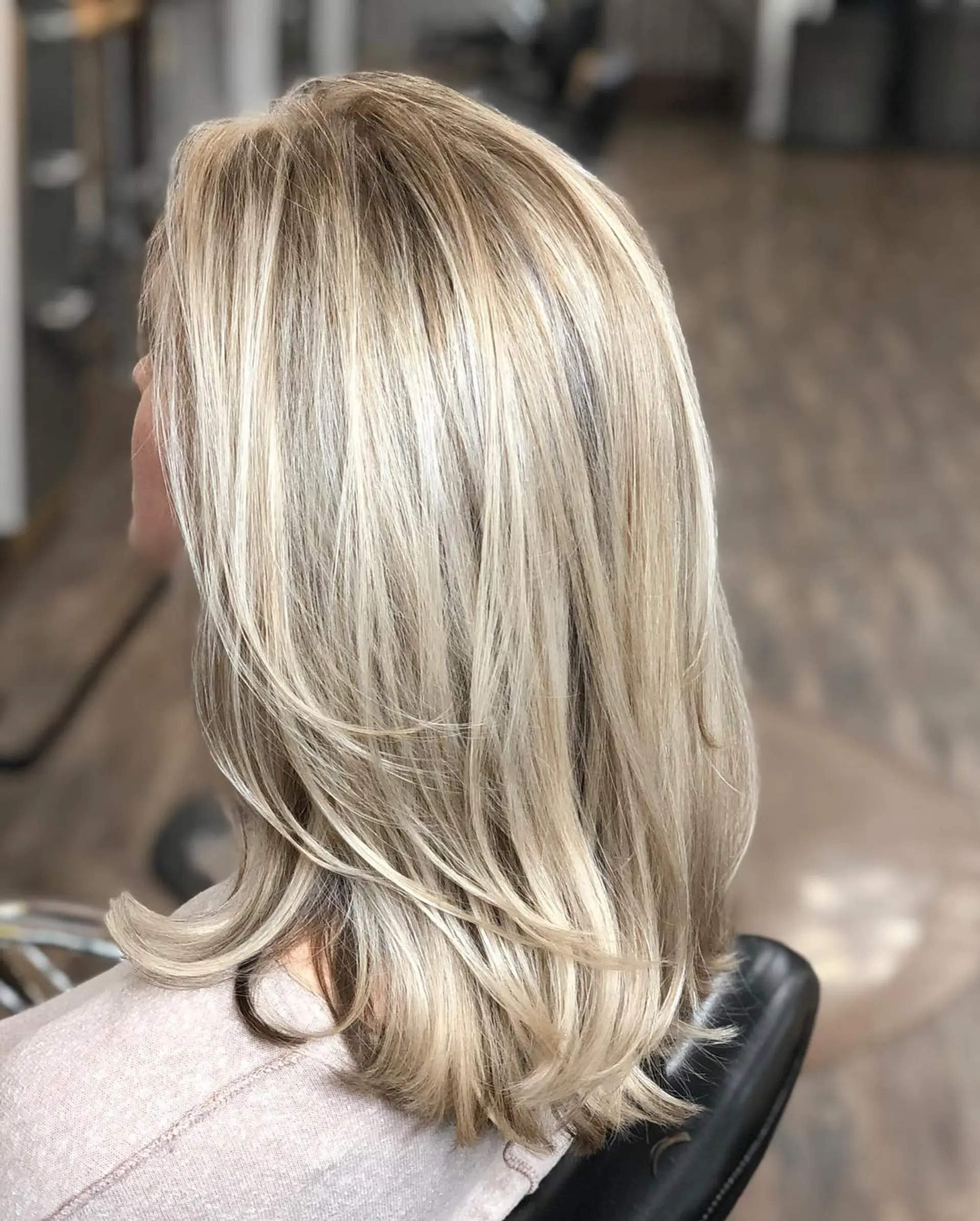 Medium-length layered cool blonde hair with dimensional highlights and softly flicked ends. 1