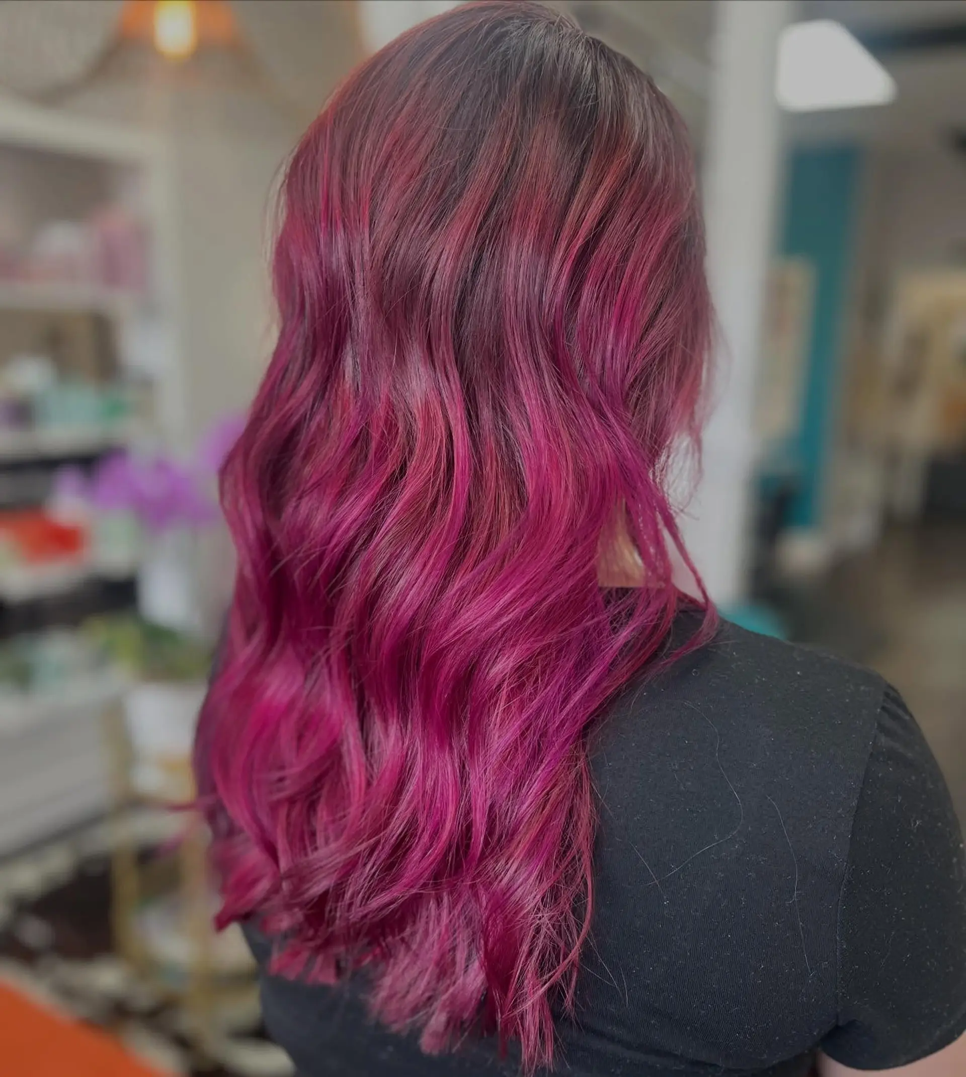Long wavy hair featuring a vibrant magenta and berry-toned fashion color melt over a dark base. 1