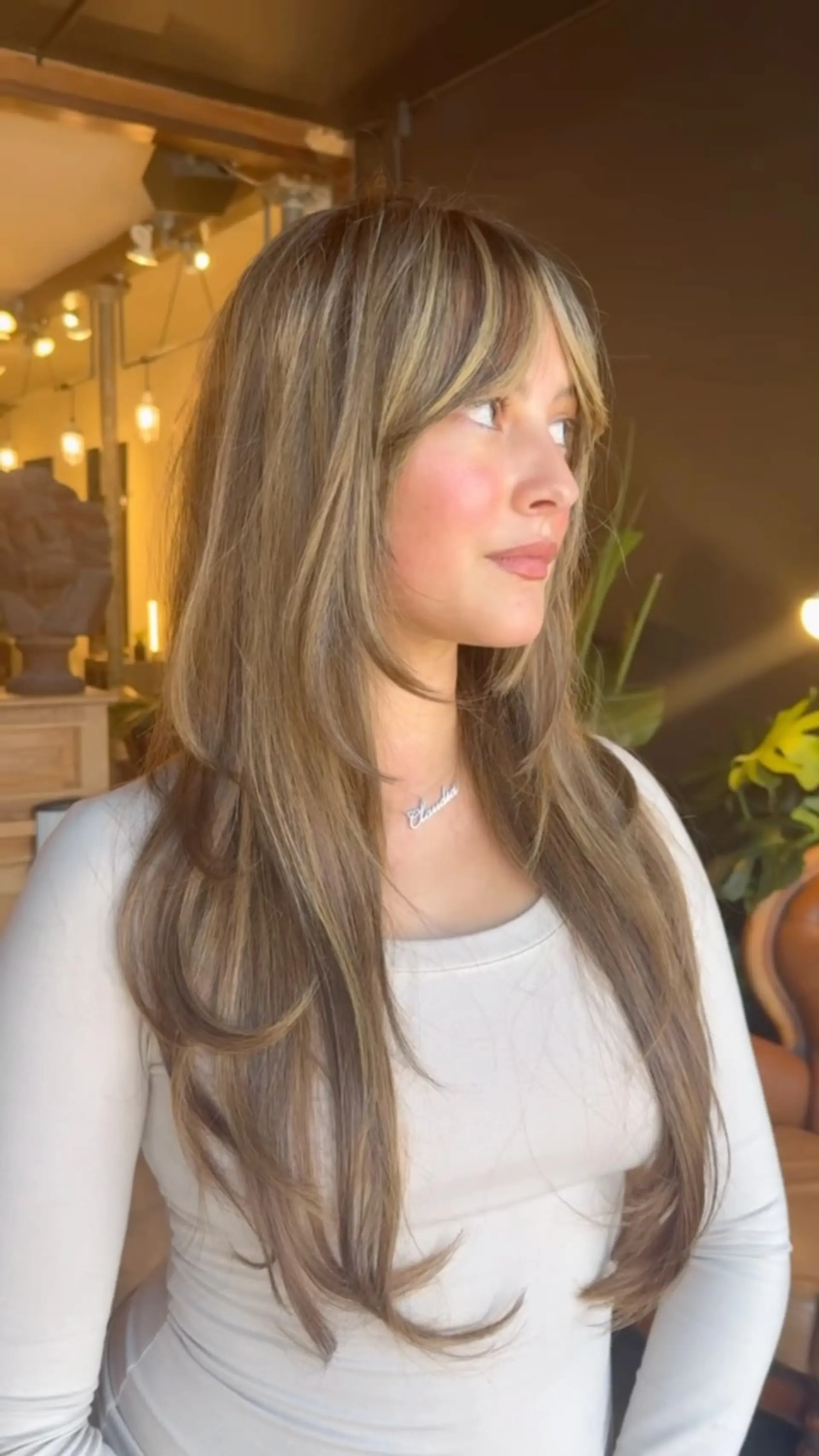 Long ash-brown hair cut with flowing tiered layers and styled with soft face-framing curtain bangs. 1