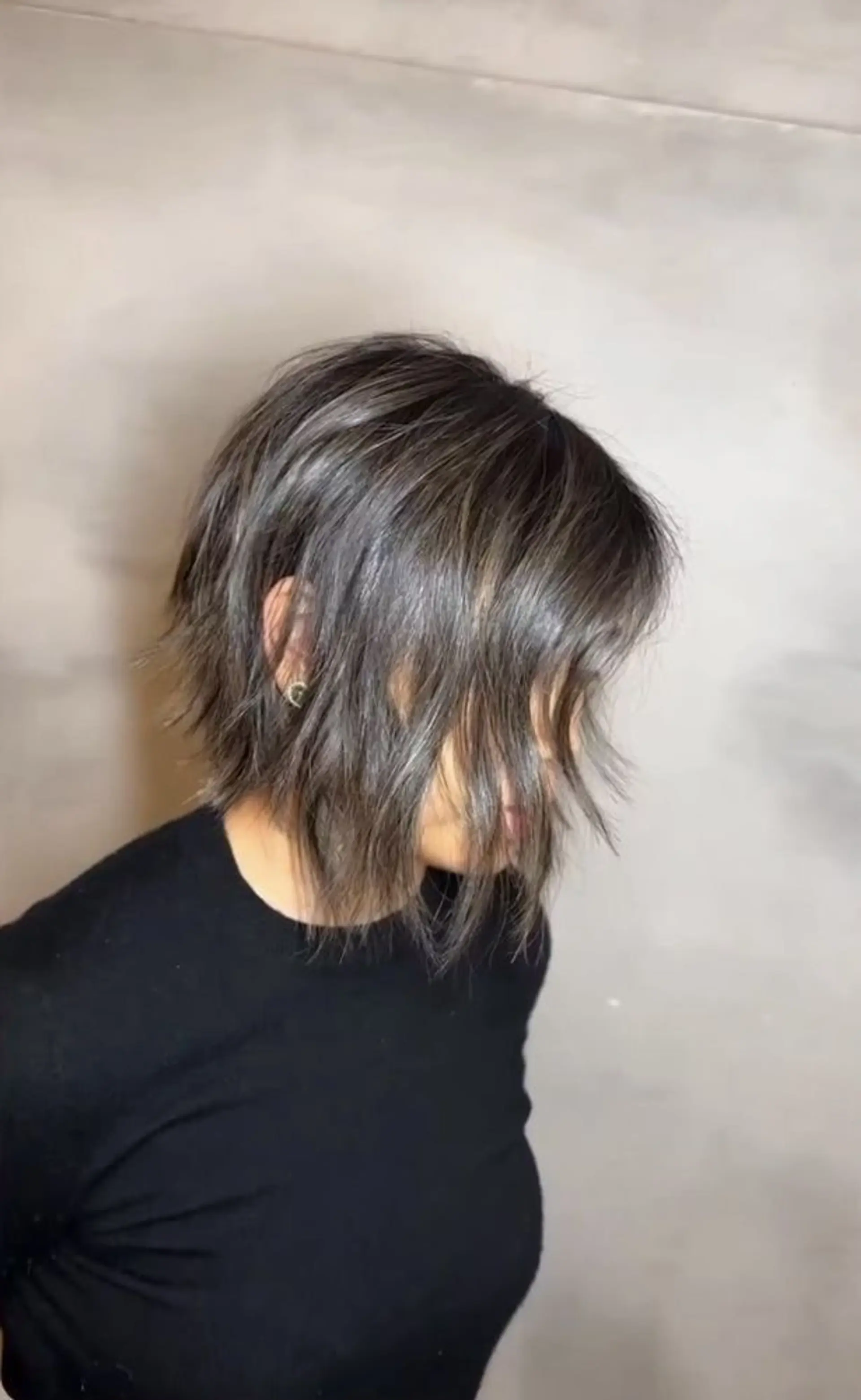A wispy chic bob cut with a wavy texture, dark brown base color with ash brown highlights, layered for volume and movement, and side-swept bangs framing the face. 1