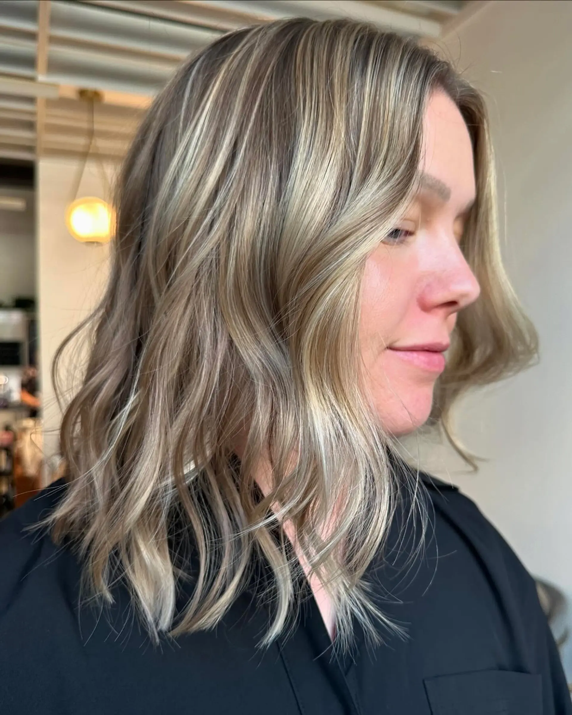 A textured shoulder-length lob featuring blended blonde highlights and soft, effortless waves. 1