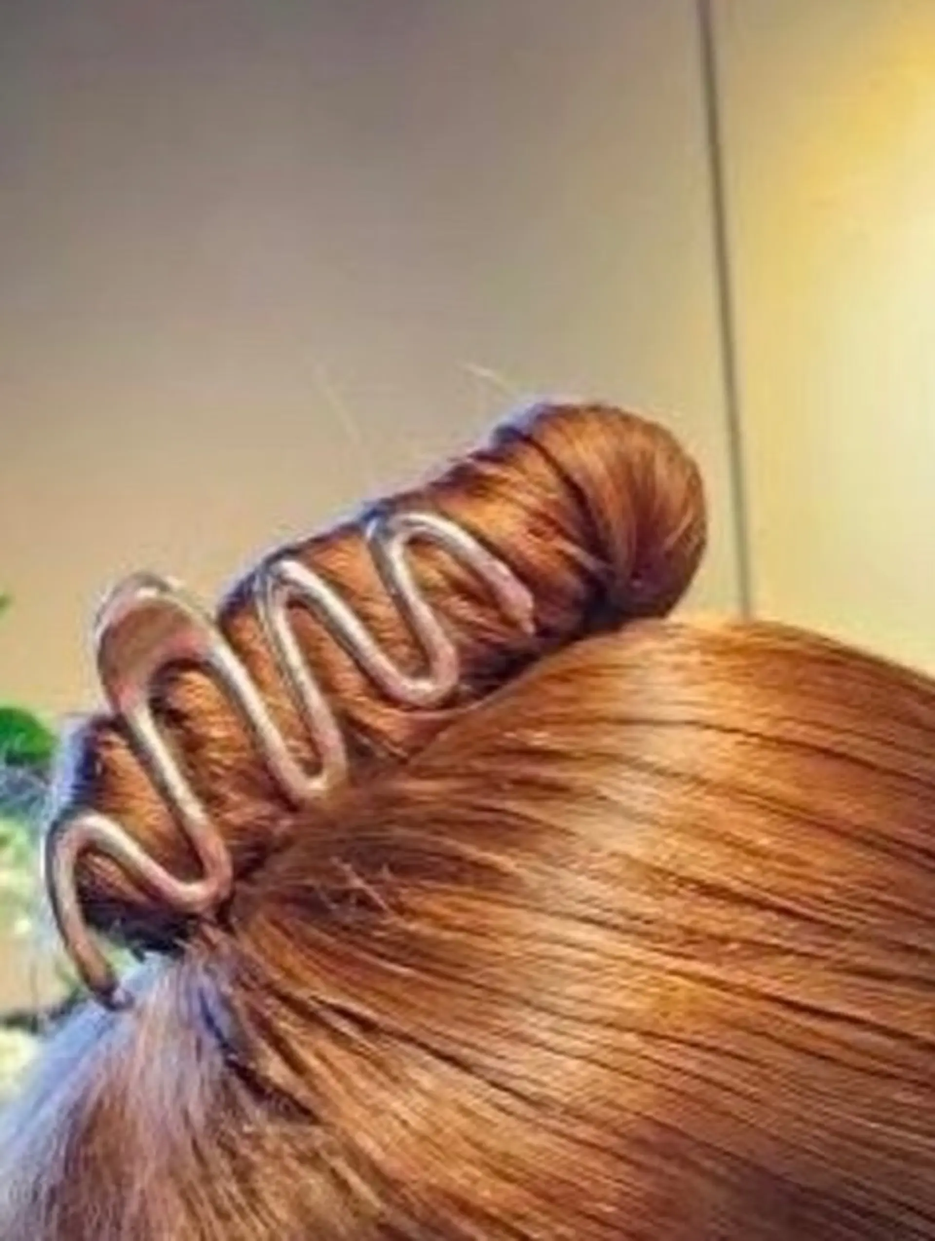 Shiny auburn hair swept up into a twist and secured with a wavy metal claw clip. 1
