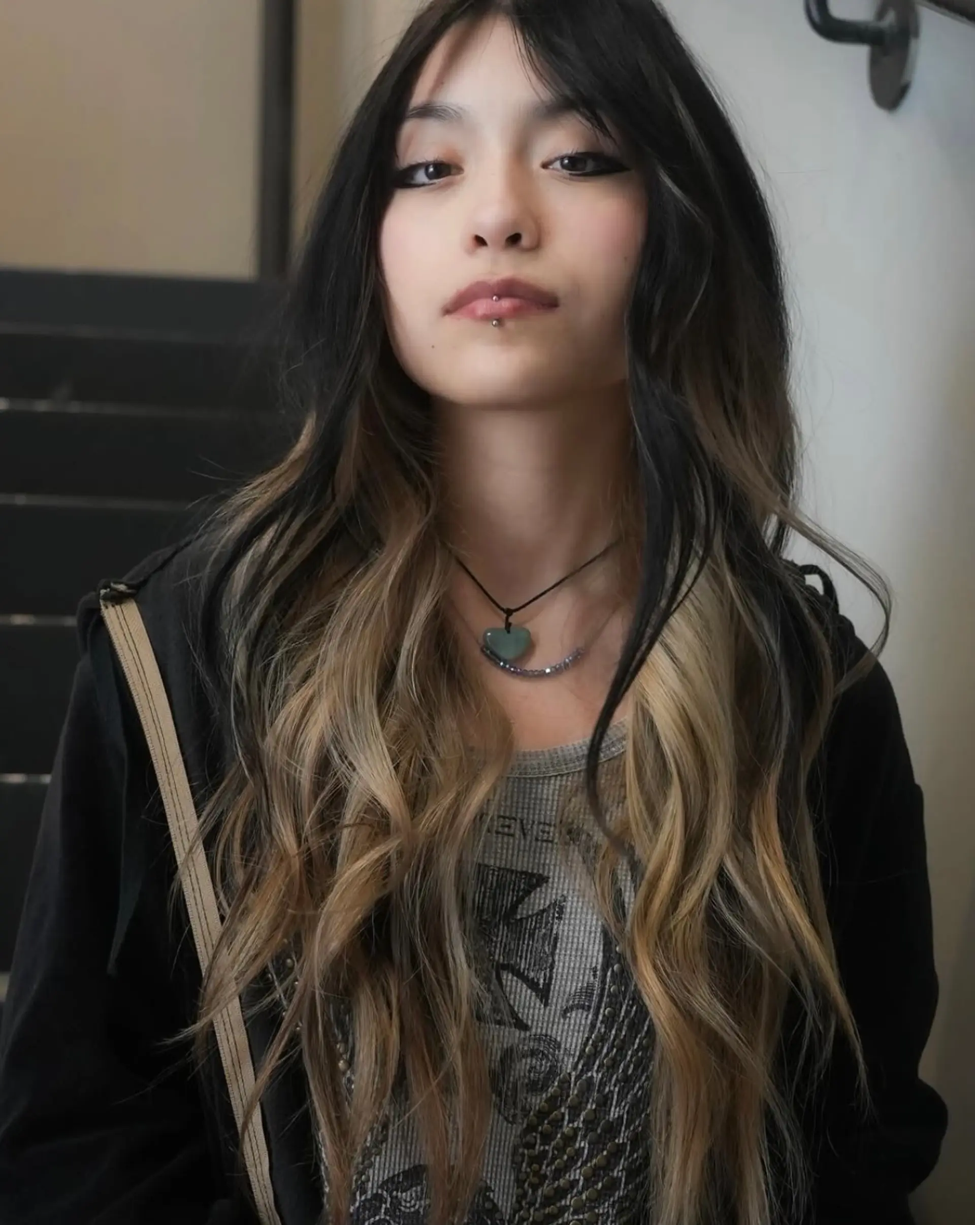 Long, layered two-tone hairstyle featuring contrasting dark black and soft blonde color blocking styled in effortless waves. 1