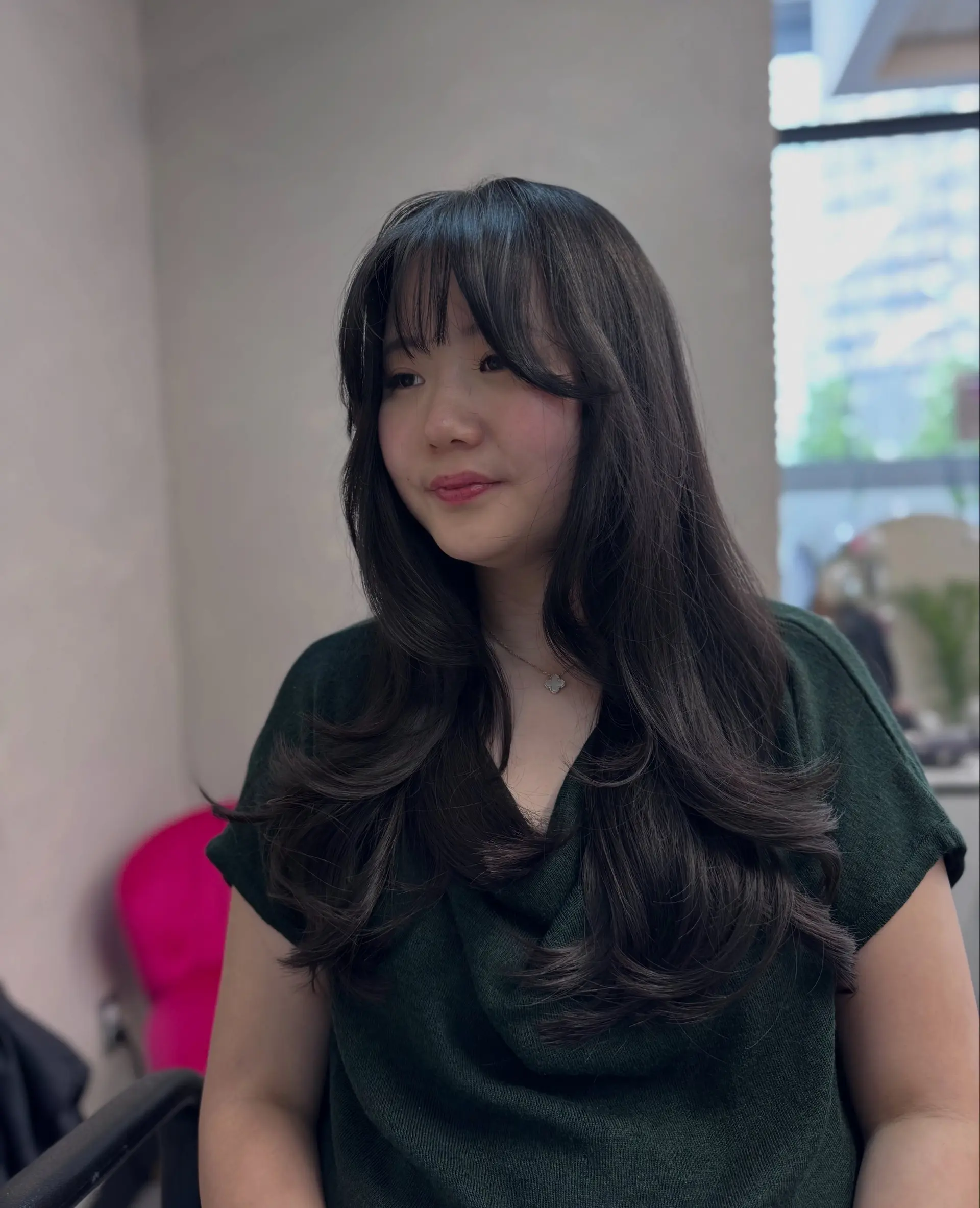 Long dark brown hair cut with soft face-framing layers, wispy bangs, and bouncy blow-dried flipped ends. 1