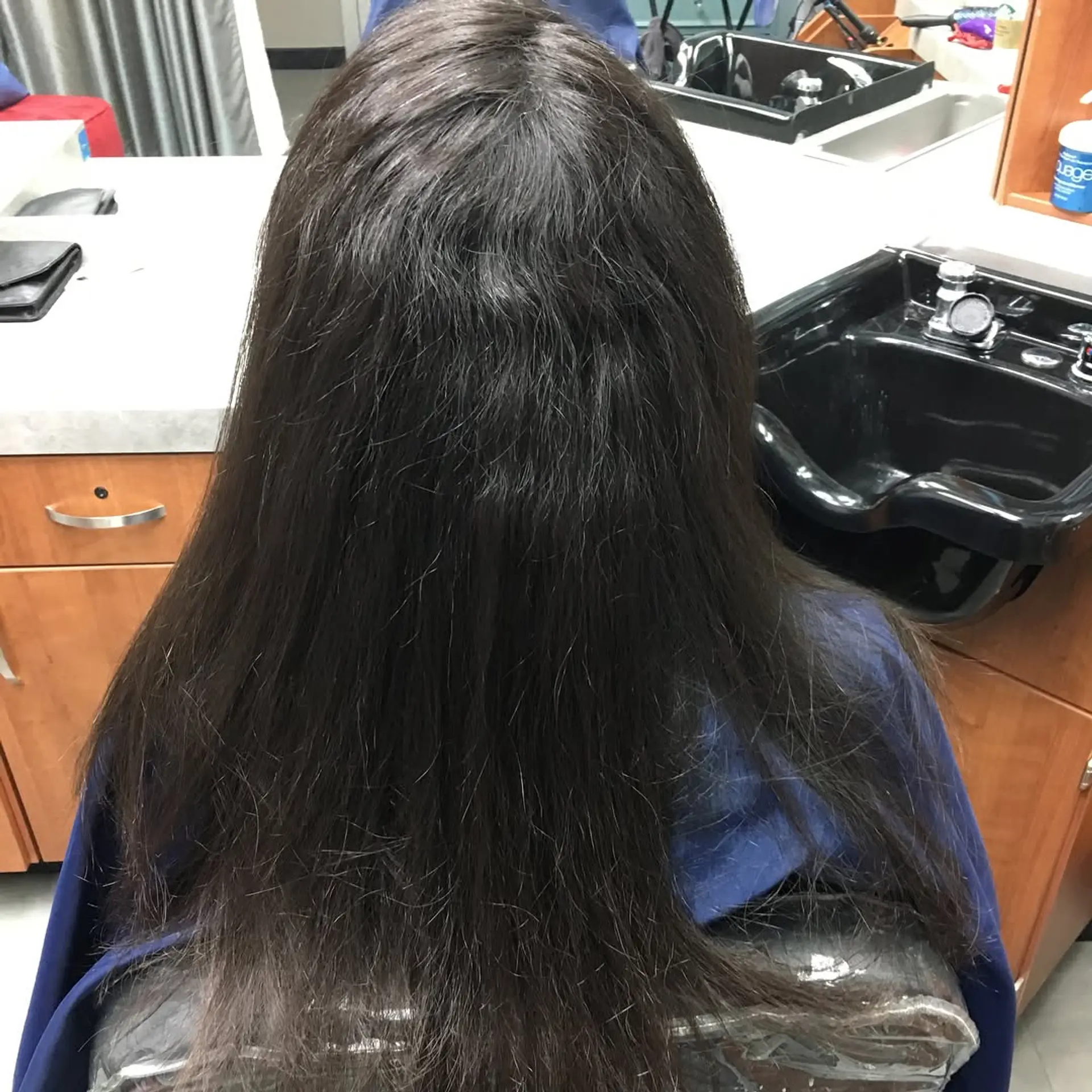 Long, naturally straight dark brown hair shown from the back after a smoothing treatment. 1