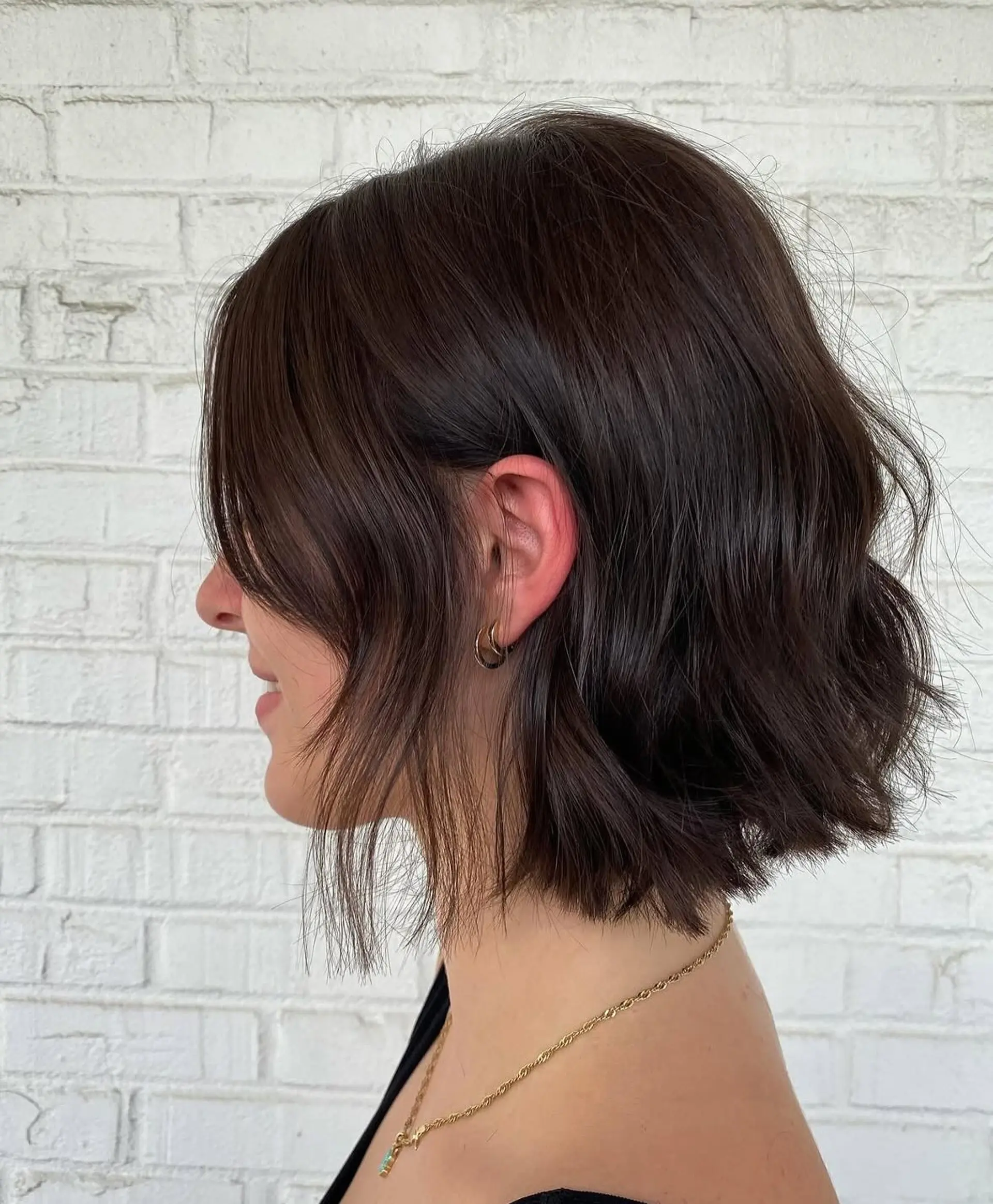 A chic, textured chin-length bob in a deep espresso brown, styled with soft, effortless waves and face-framing wisps. 1