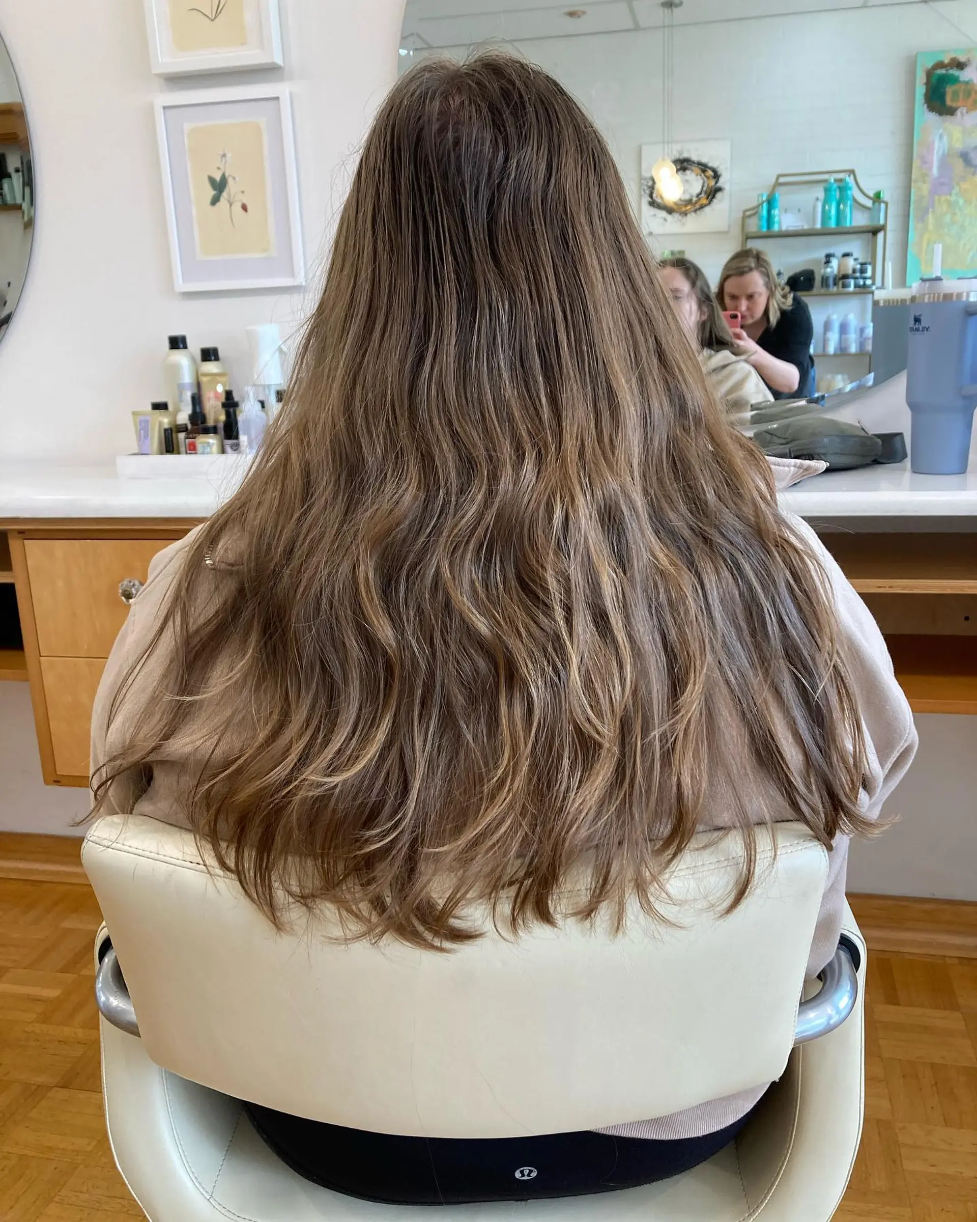 Long light brown hair detailed with subtle cool blonde highlights and styled in soft natural waves. 1