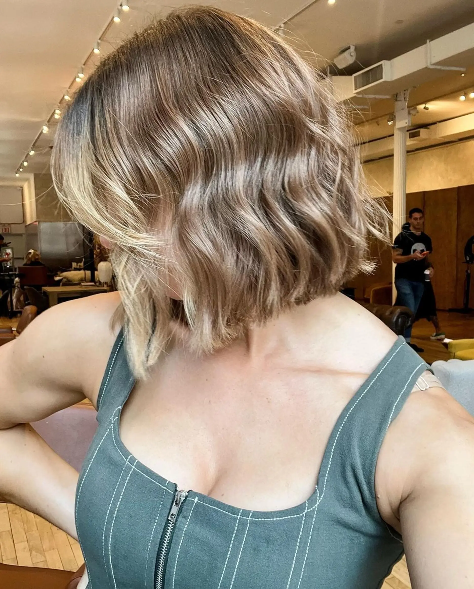 Shoulder-length wavy bob with soft golden blonde highlights over a light brown base, featuring beach waves and a textured finish. 2