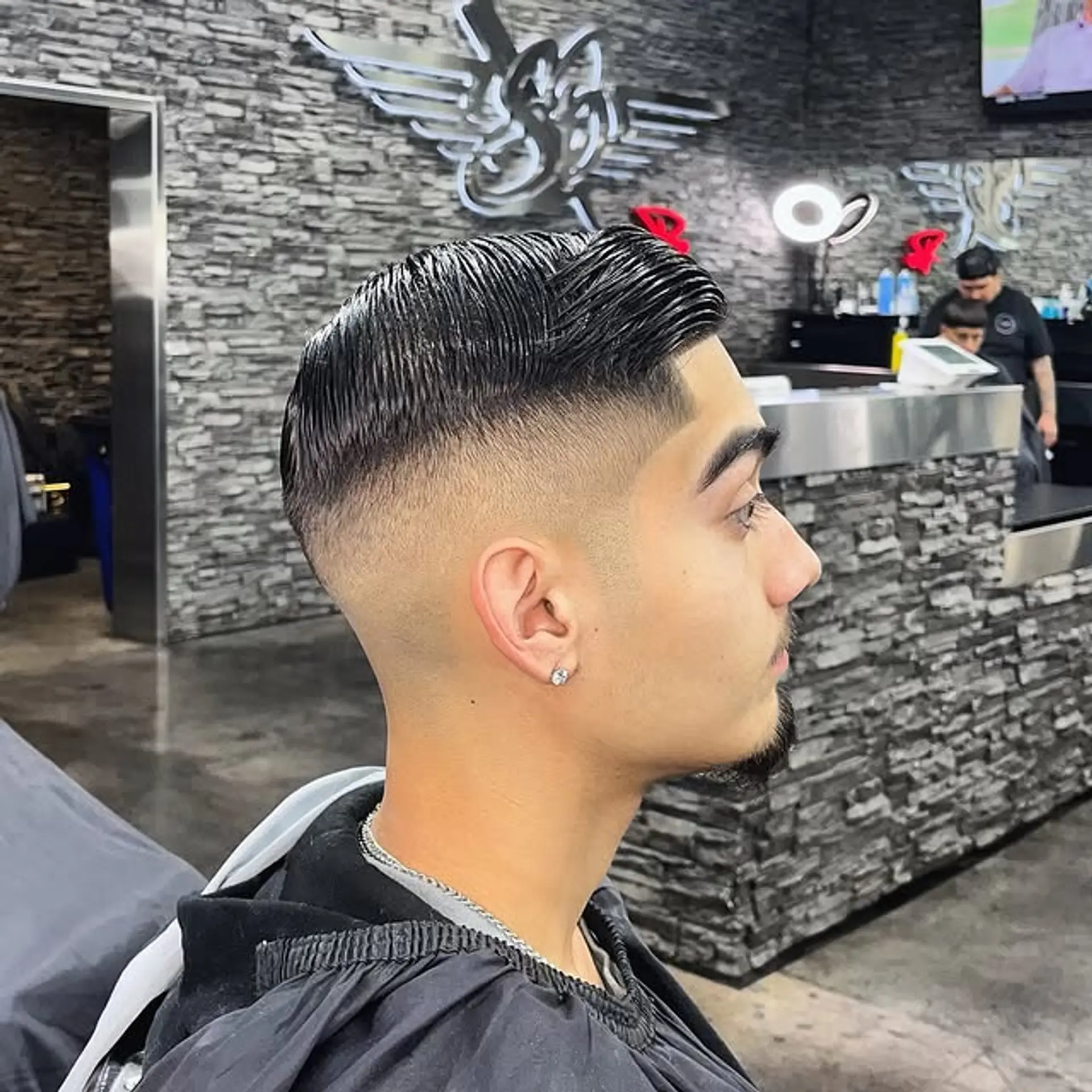 A modern fade with tapered sides, neatly styled into a slicked-back. 1