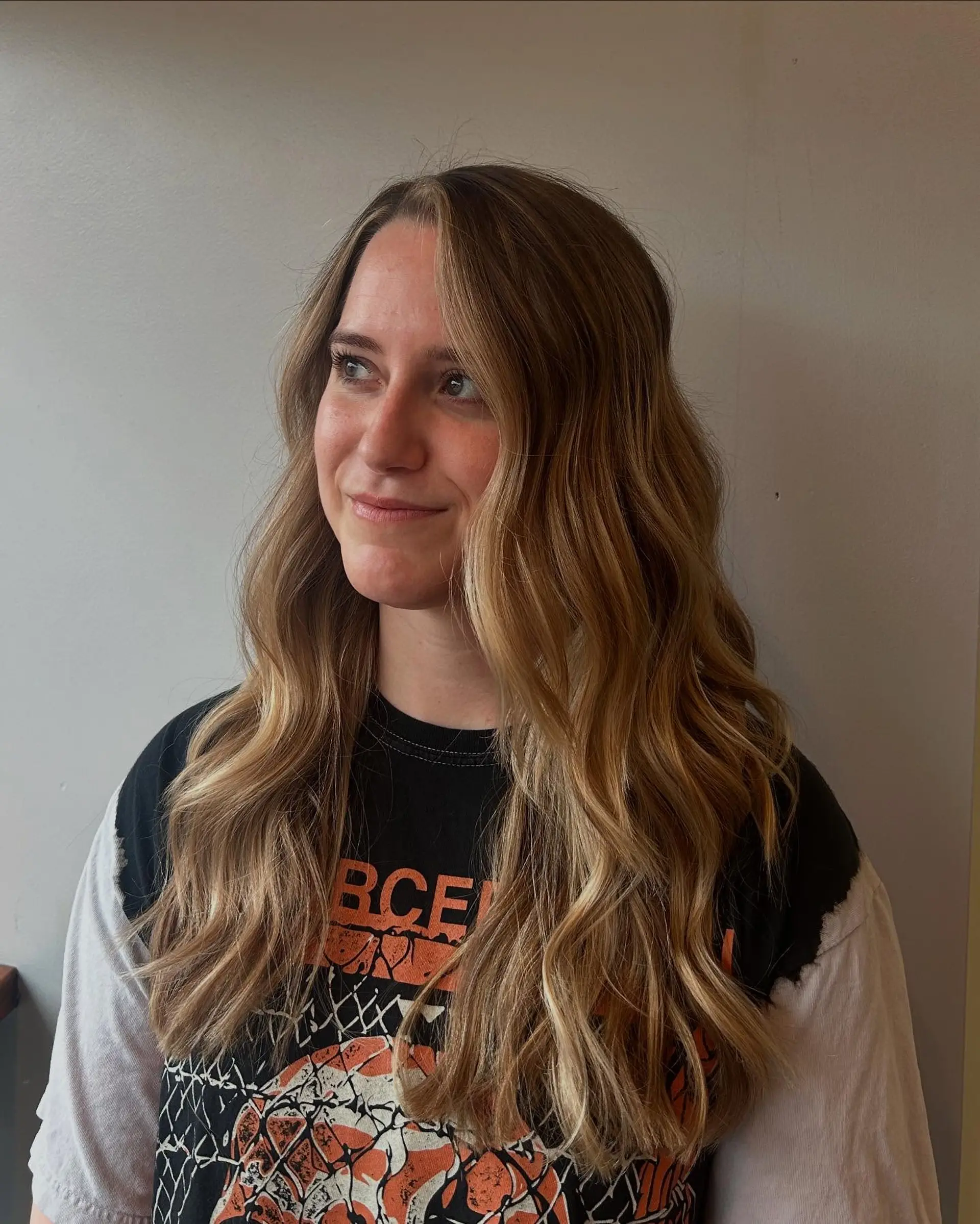 Long dimensional blonde hair styled into loose, effortless beach waves with a bright face-framing money piece. 1