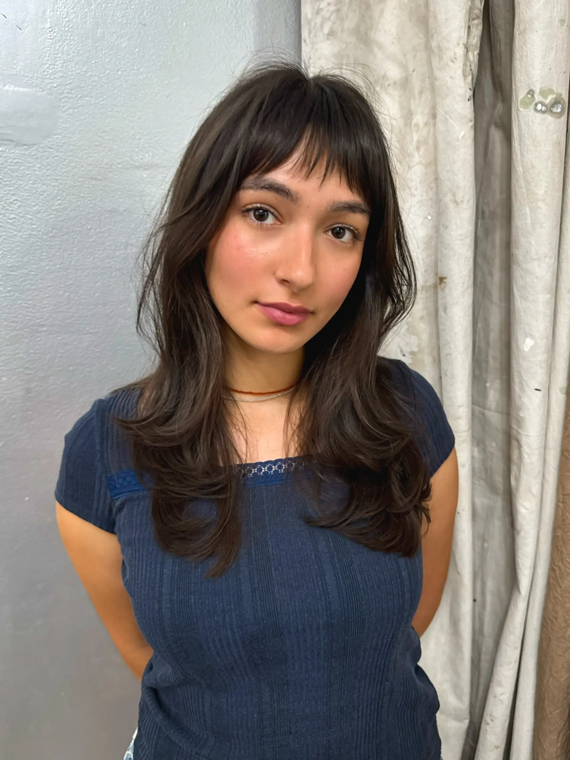 A medium-length layered haircut with curtain bangs and face-framing layers. 1