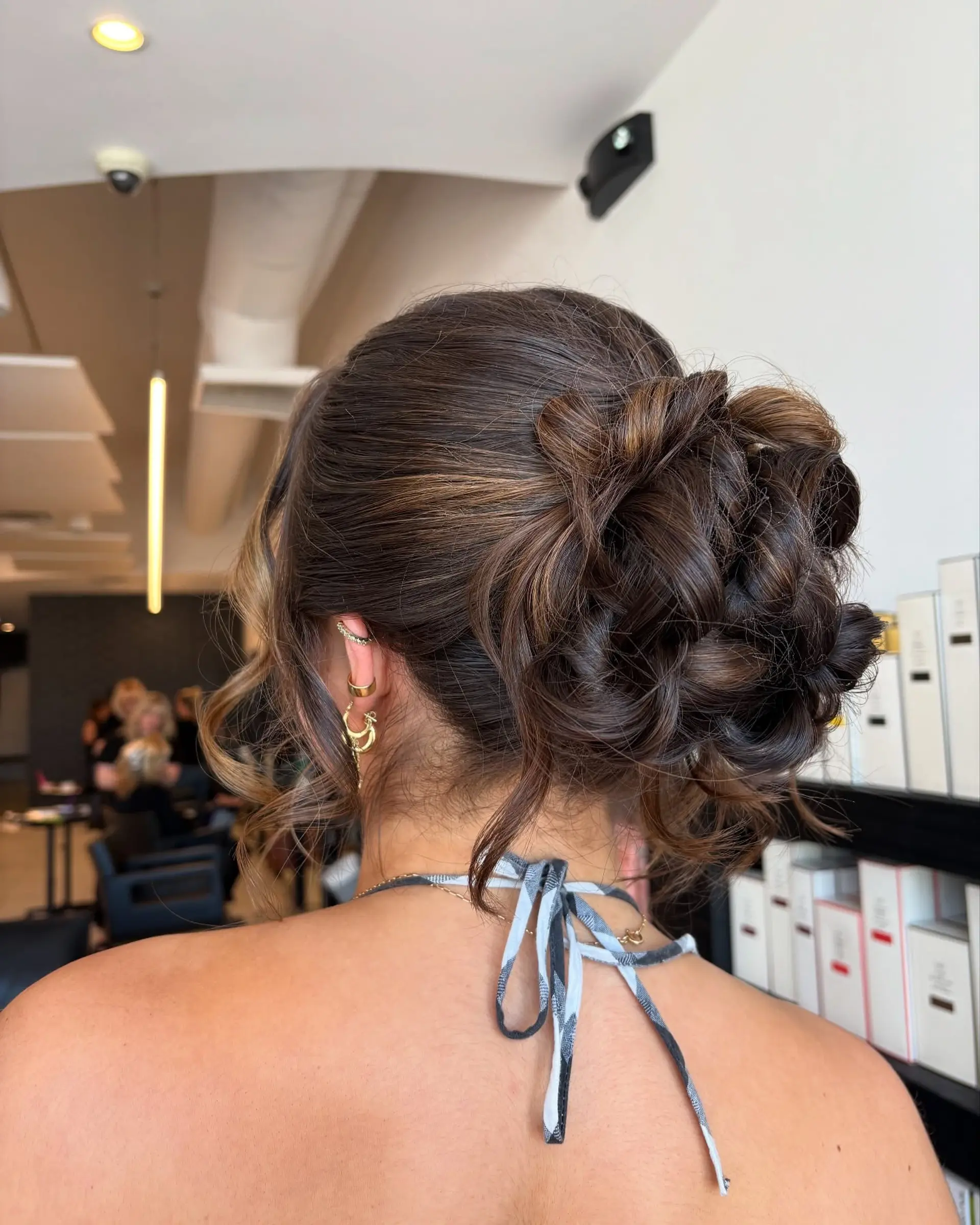 A romantic, textured low updo featuring pinned curls and soft tendrils. 1