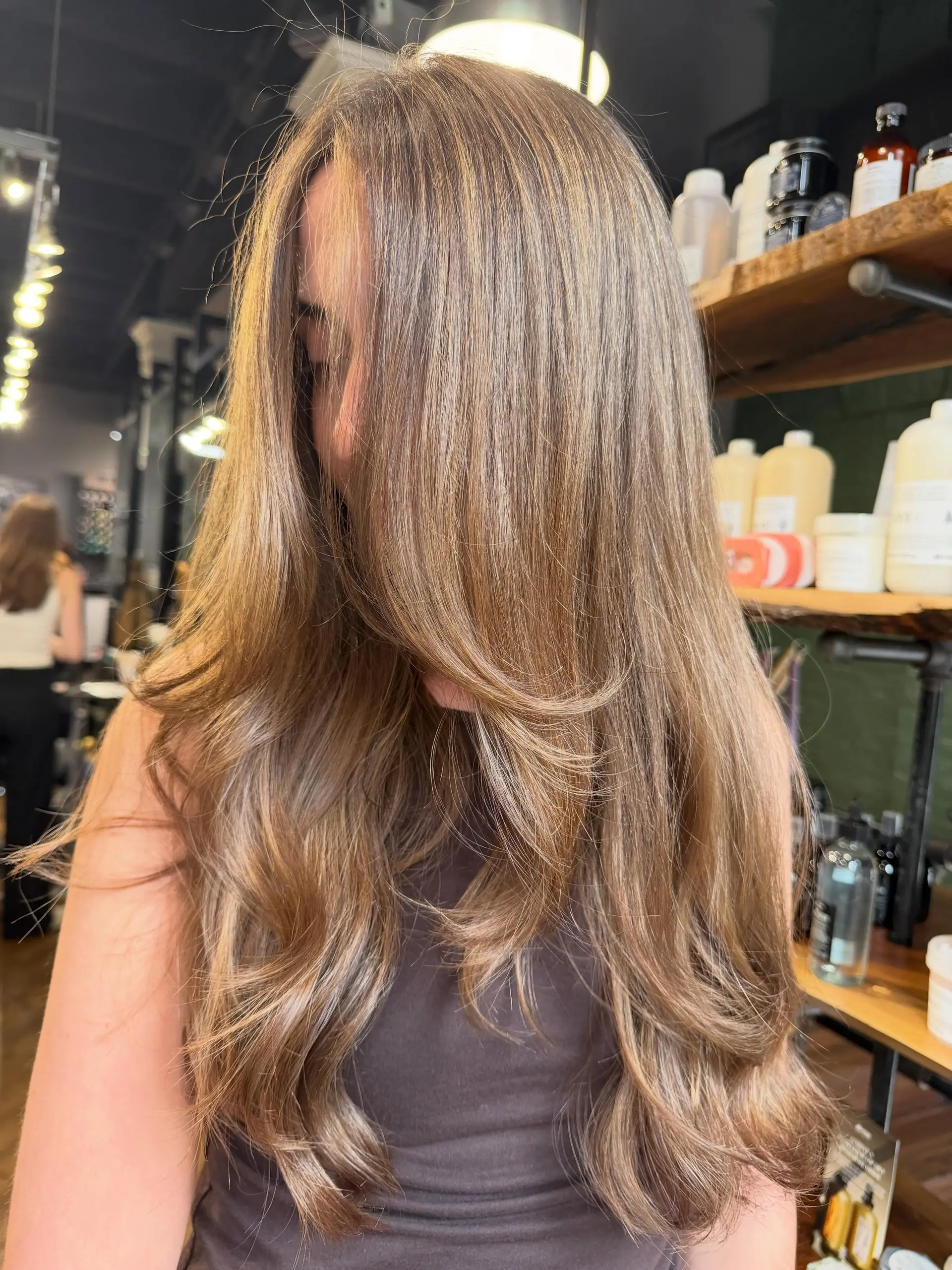 A lush, long haircut featuring face-framing layers and soft blowout waves in a multi-tonal light brunette shade. 1