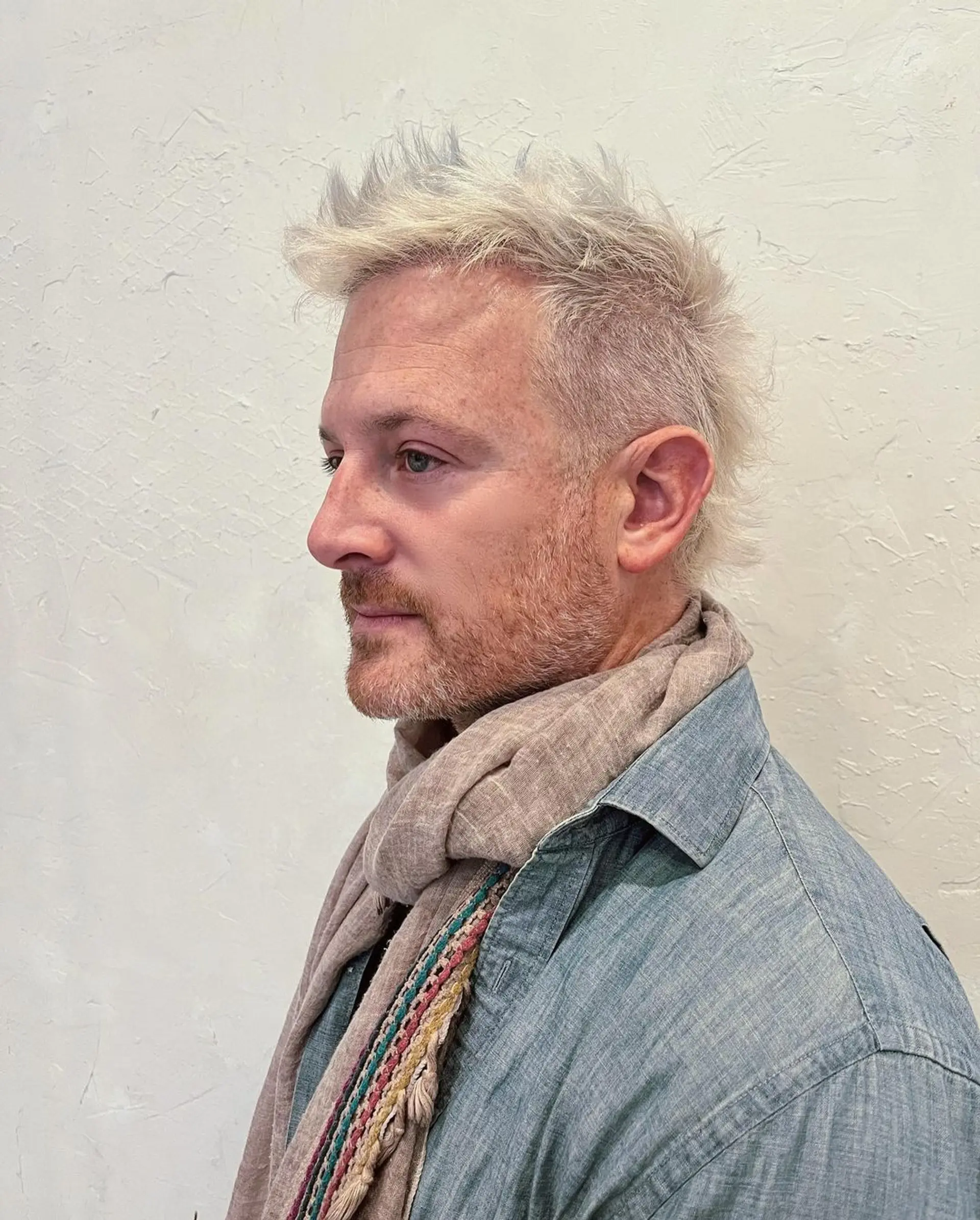 Short, platinum blonde hair with faded sides and a textured top. The fringe is styled into a pointed quiff. 1