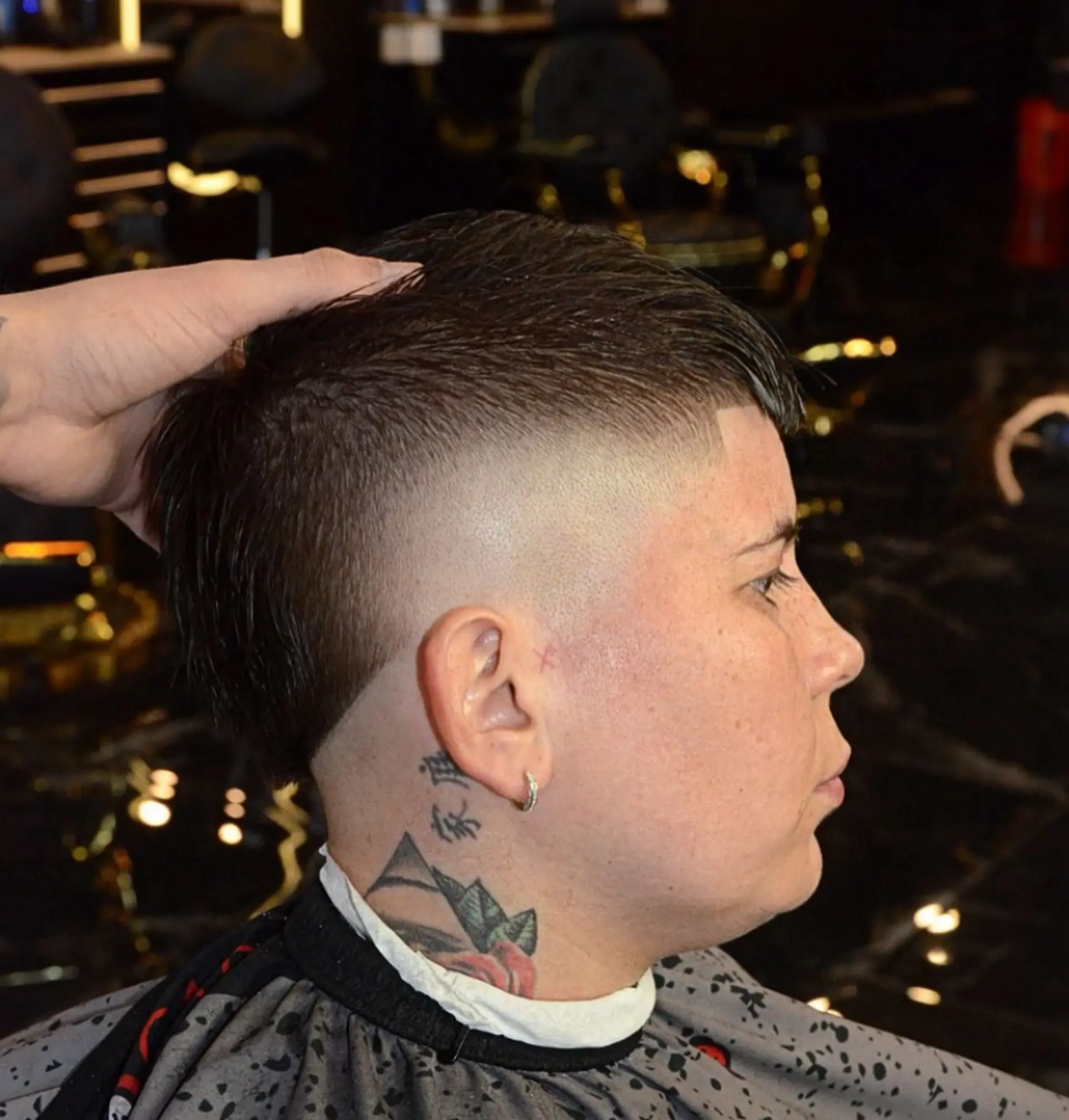 A modern mullet cut featuring a high bald fade on the sides, sharp edge-up at the temples, and textured length down the crown and back. 1