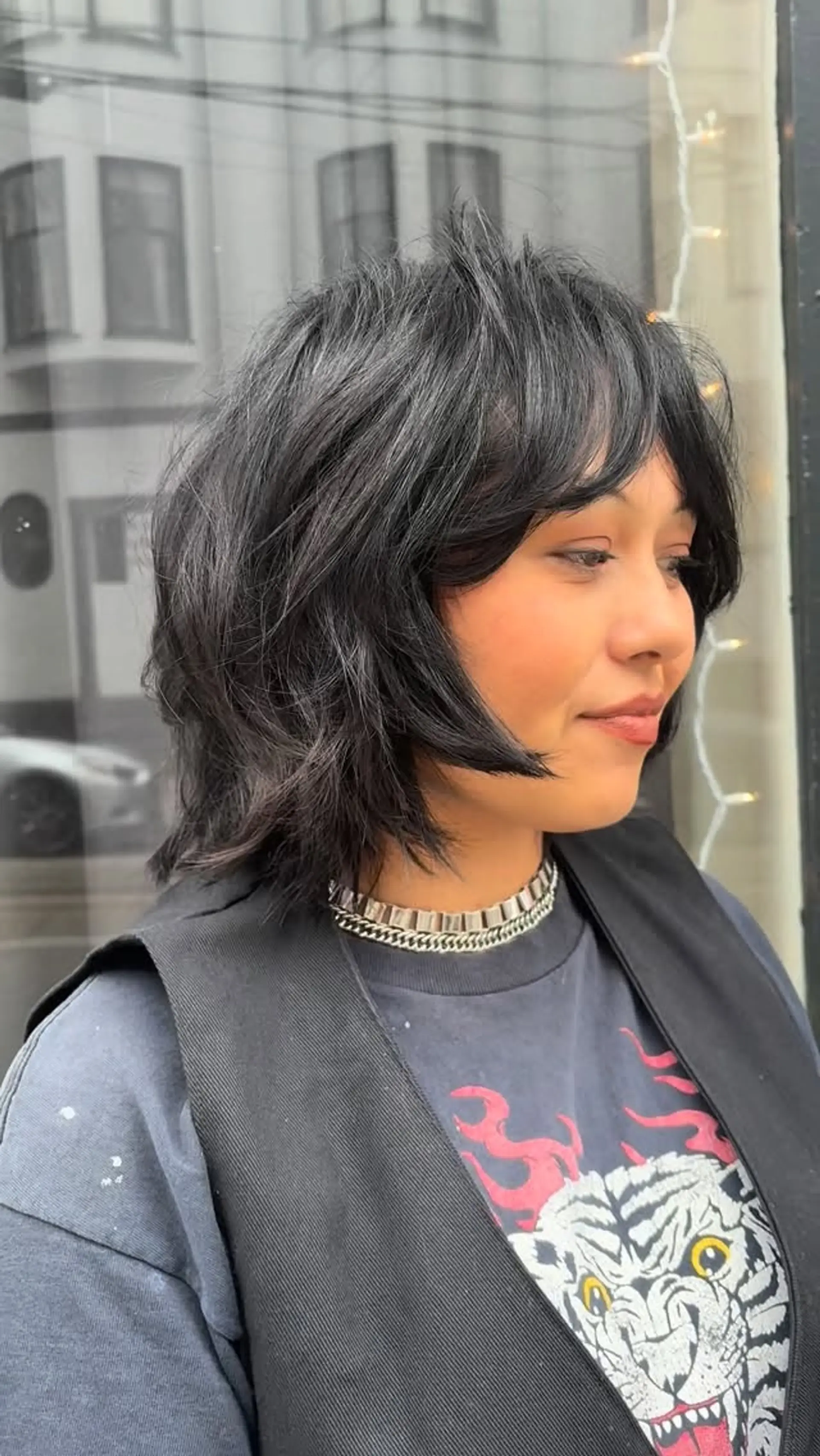 A short, neck-length shag cut dyed deep black, complete with textured layers and soft curtain bangs framing the face. 1