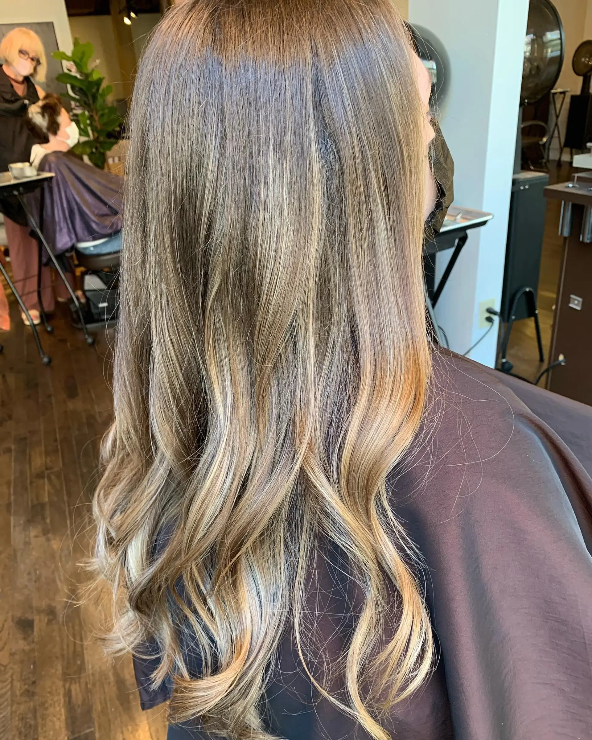 A long, layered hairstyle with soft, beachy waves and a balayage color melt. 1