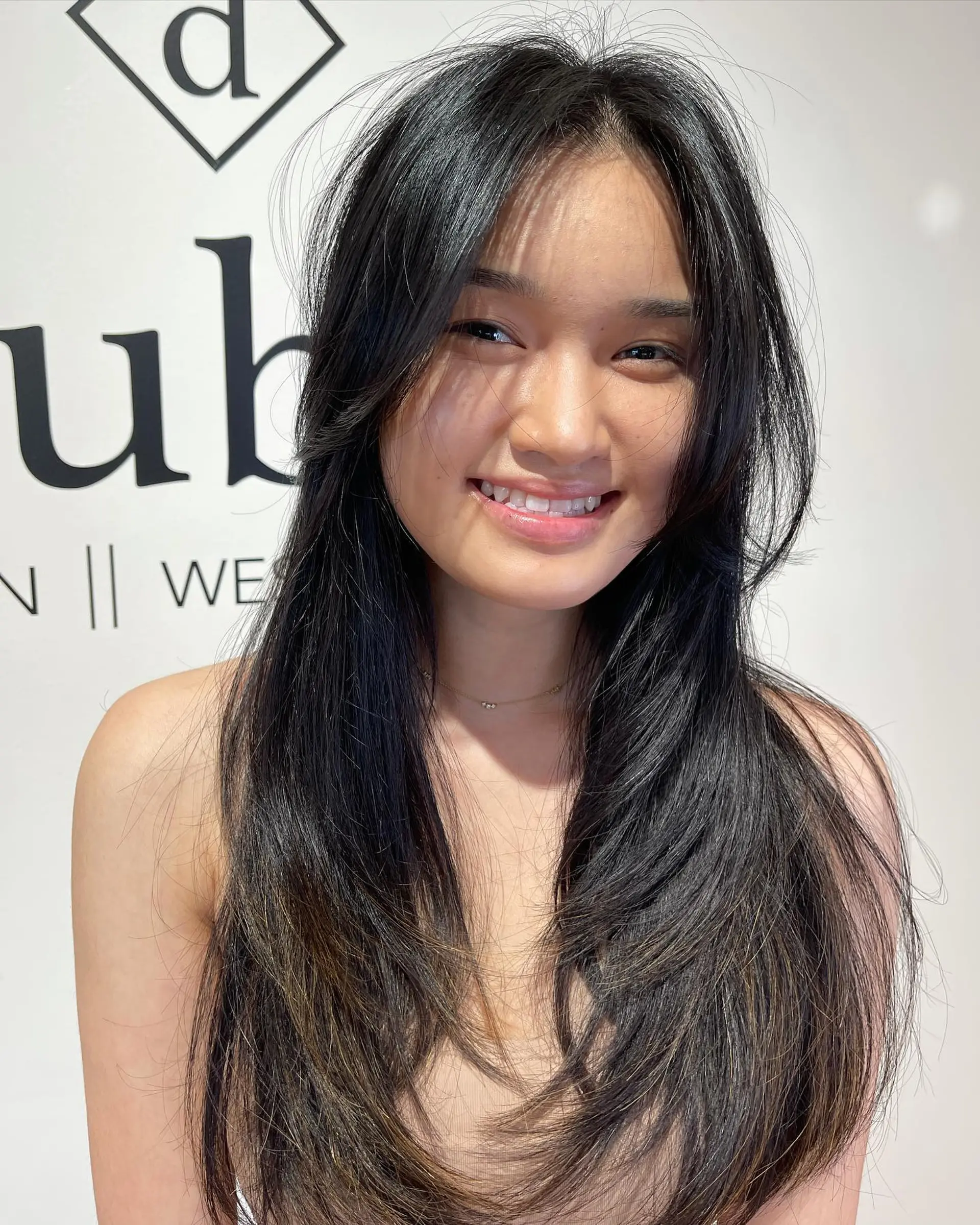 Long dark layered haircut with face-framing curtain bangs and feathered ends. 1