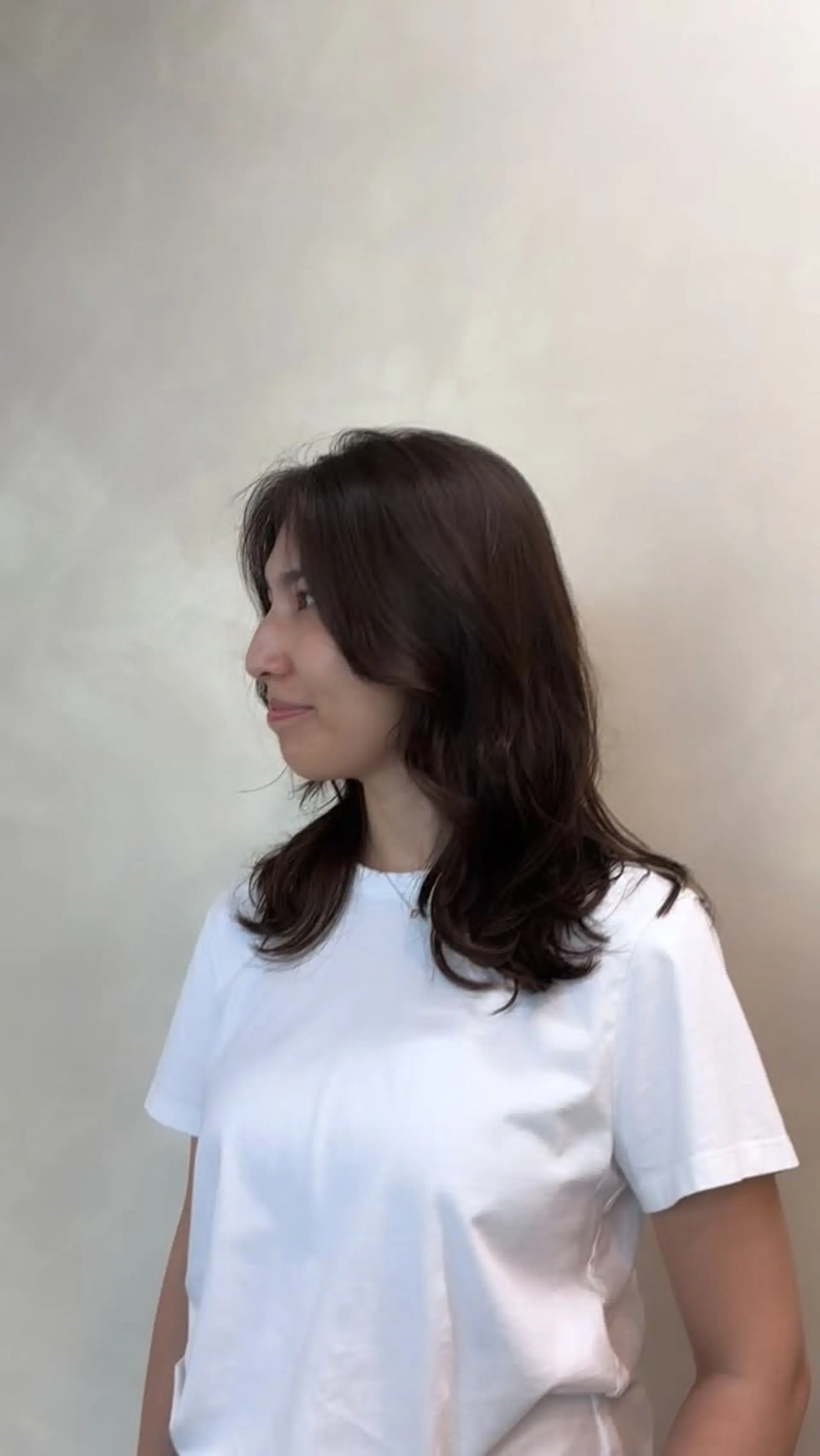 Medium-length layered brunette hair styled with soft, natural C-curls at the ends and face-framing layers. 1