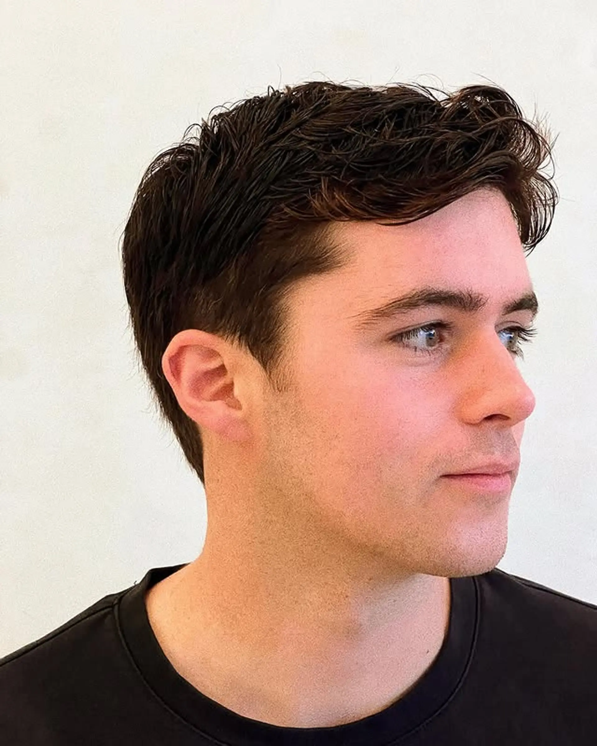 A short, textured hairstyle with tapered sides and back. 1