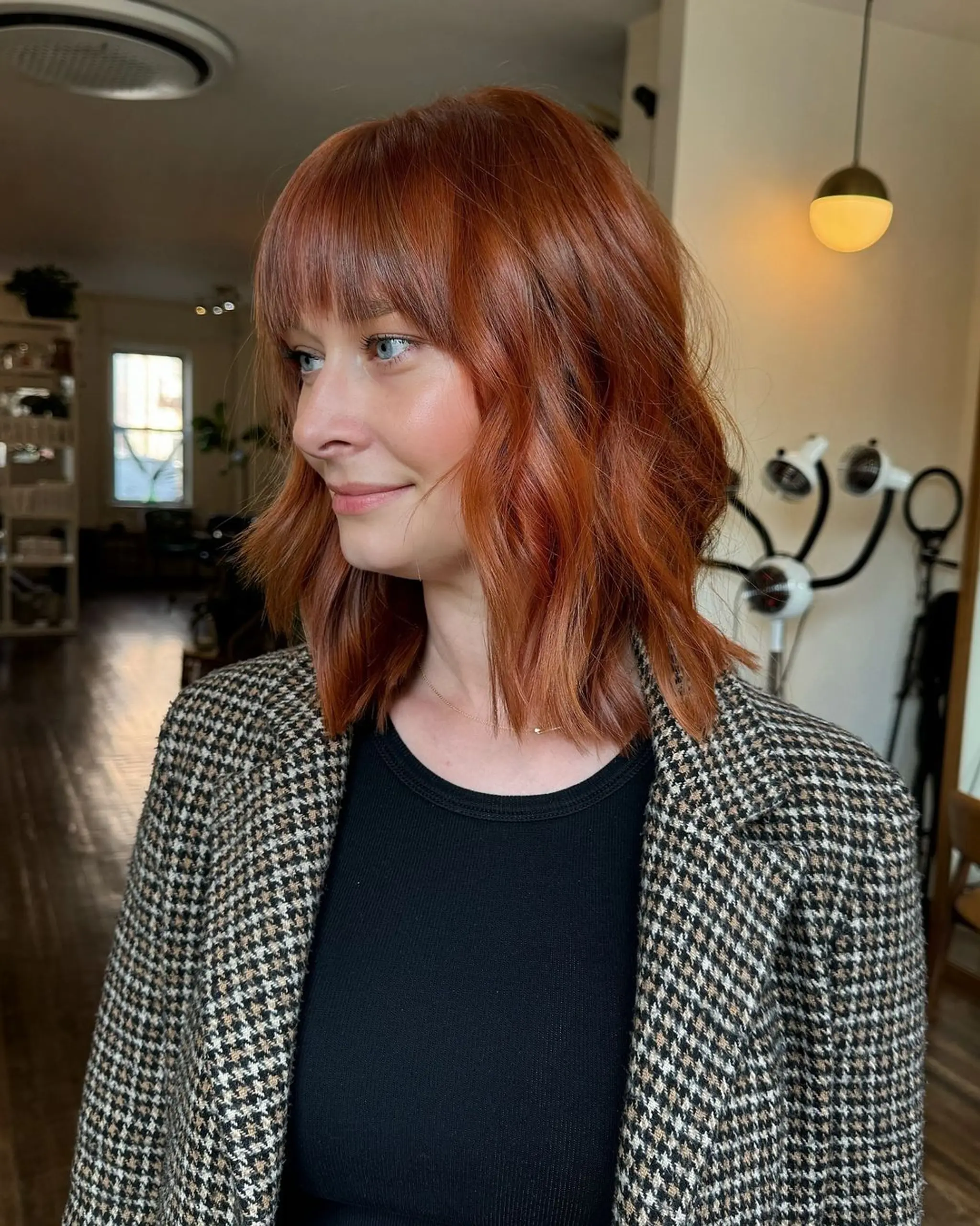 Medium-length wavy bob with copper color, textured ends, and fringe.