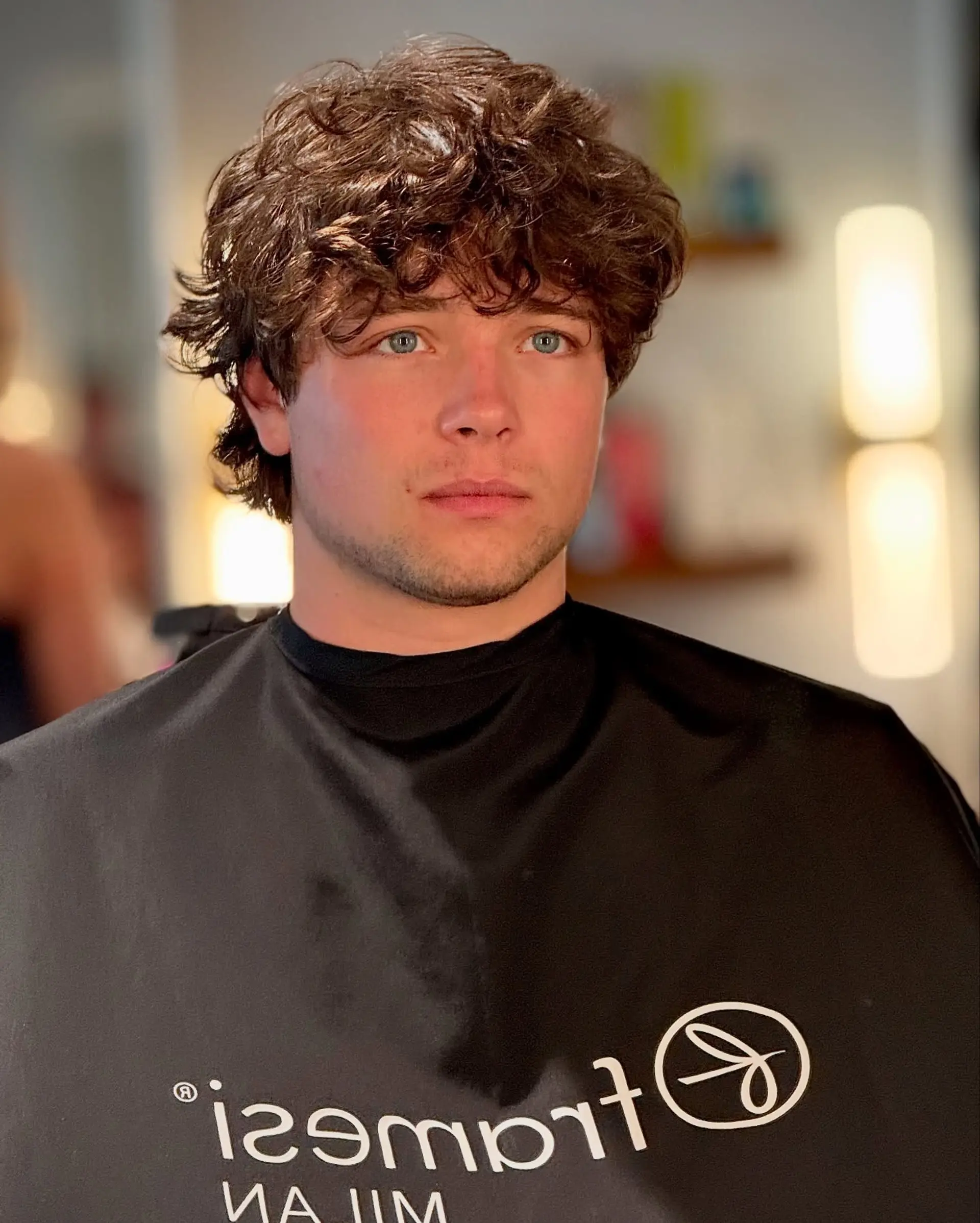 A textured short haircut highlighting natural curls and waves, styled forward with a tousled fringe covering the forehead. 1