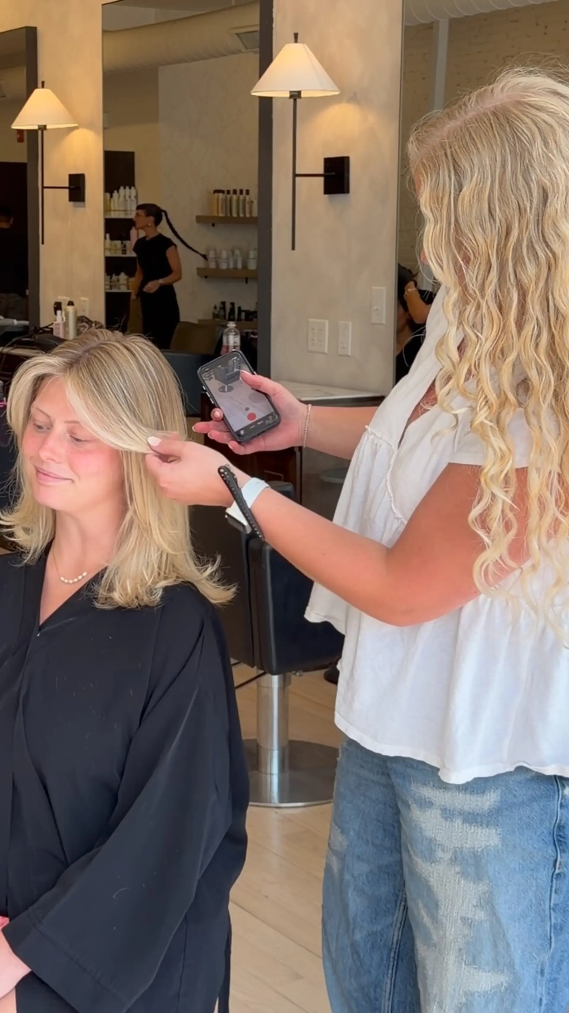 Medium-length dimensional blonde hair styled into a smooth blowout with layered curtain bangs framing the face. 1