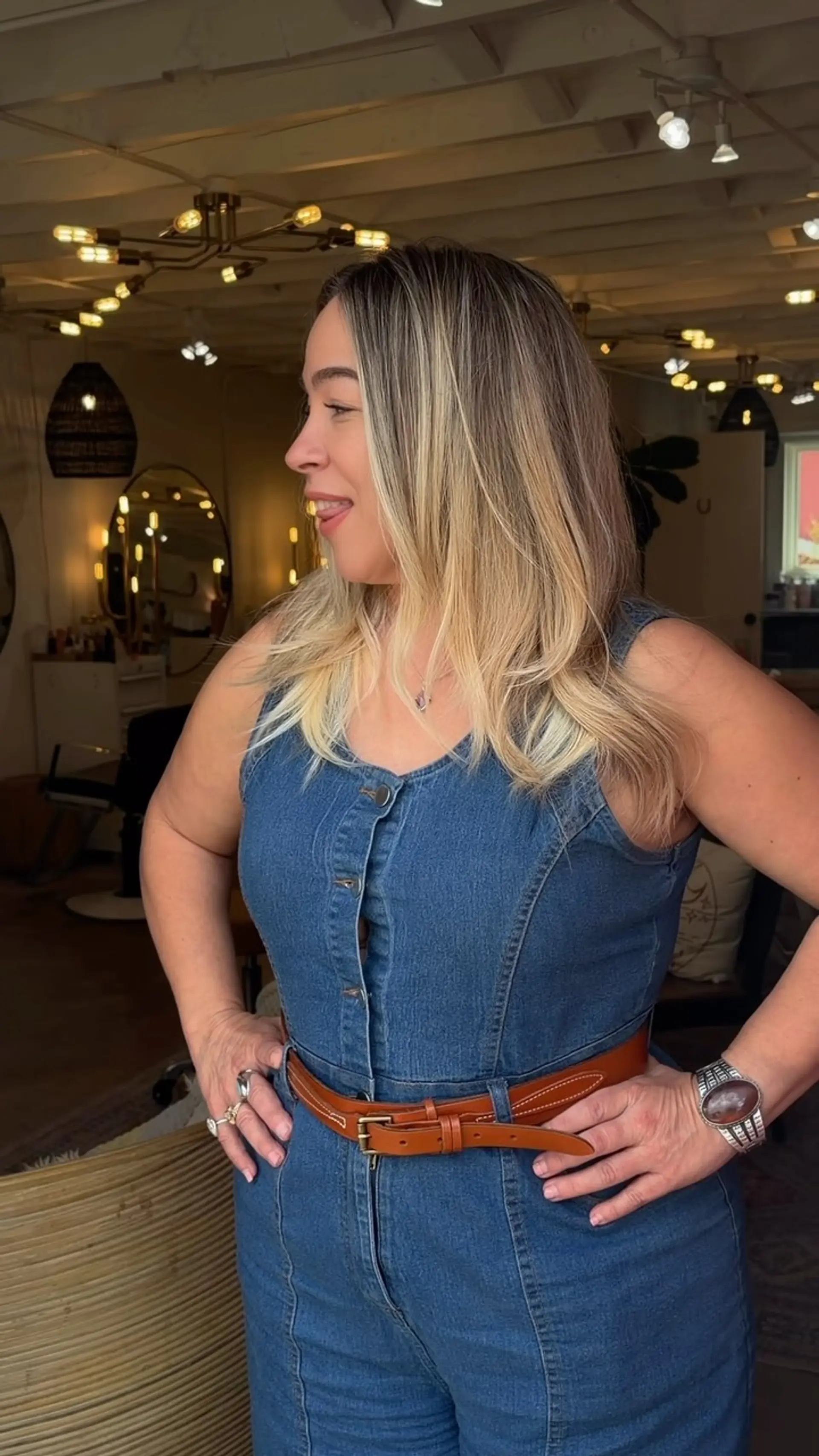 Medium-length layered haircut styled into a soft blowout with lightly flipped ends, featuring warm blonde balayage highlights over a natural darker base. 1