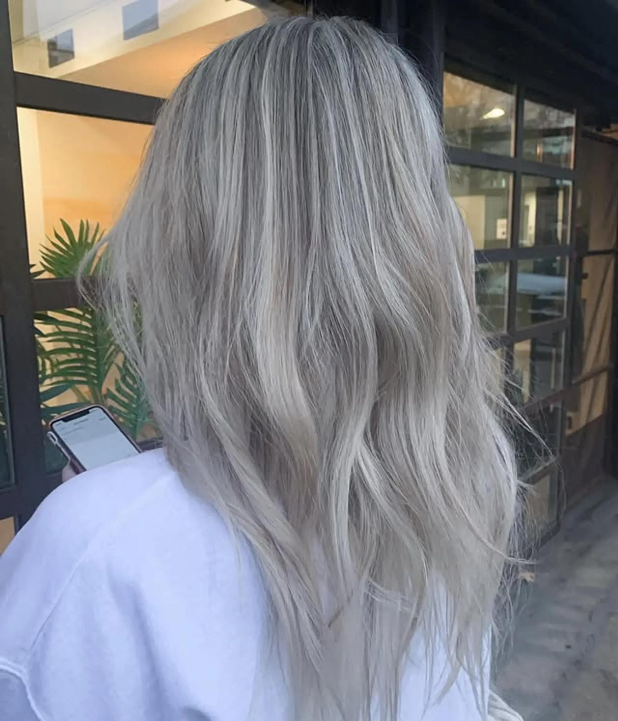 Long, straight hair with a trendy icy blonde balayage featuring platinum blonde and silver hues.