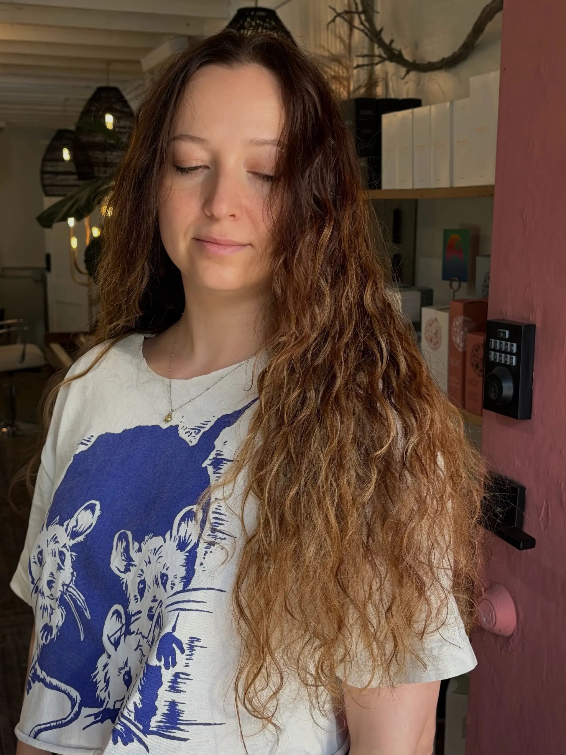 Long natural curls enhanced with warm caramel and golden balayage highlights fading softly from a dark brunette base. 1