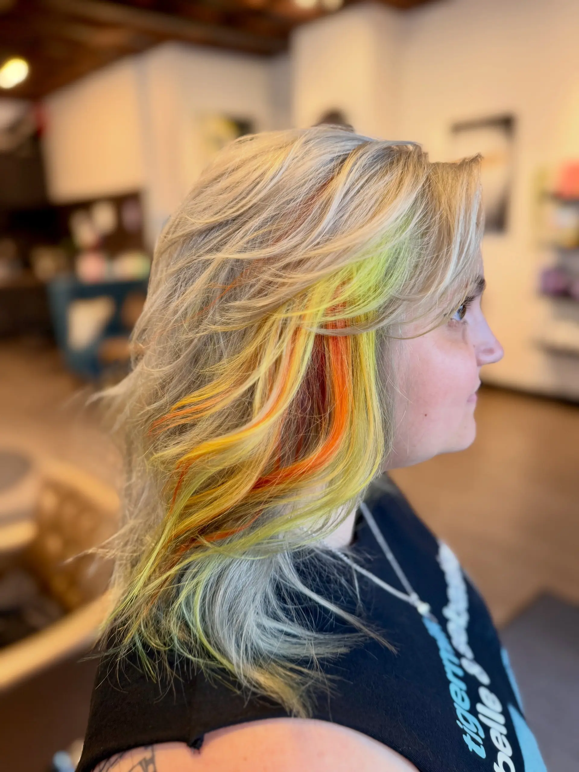 Medium-length layered blonde hair featuring vibrant yellow and orange peekaboo highlights around the face. 1