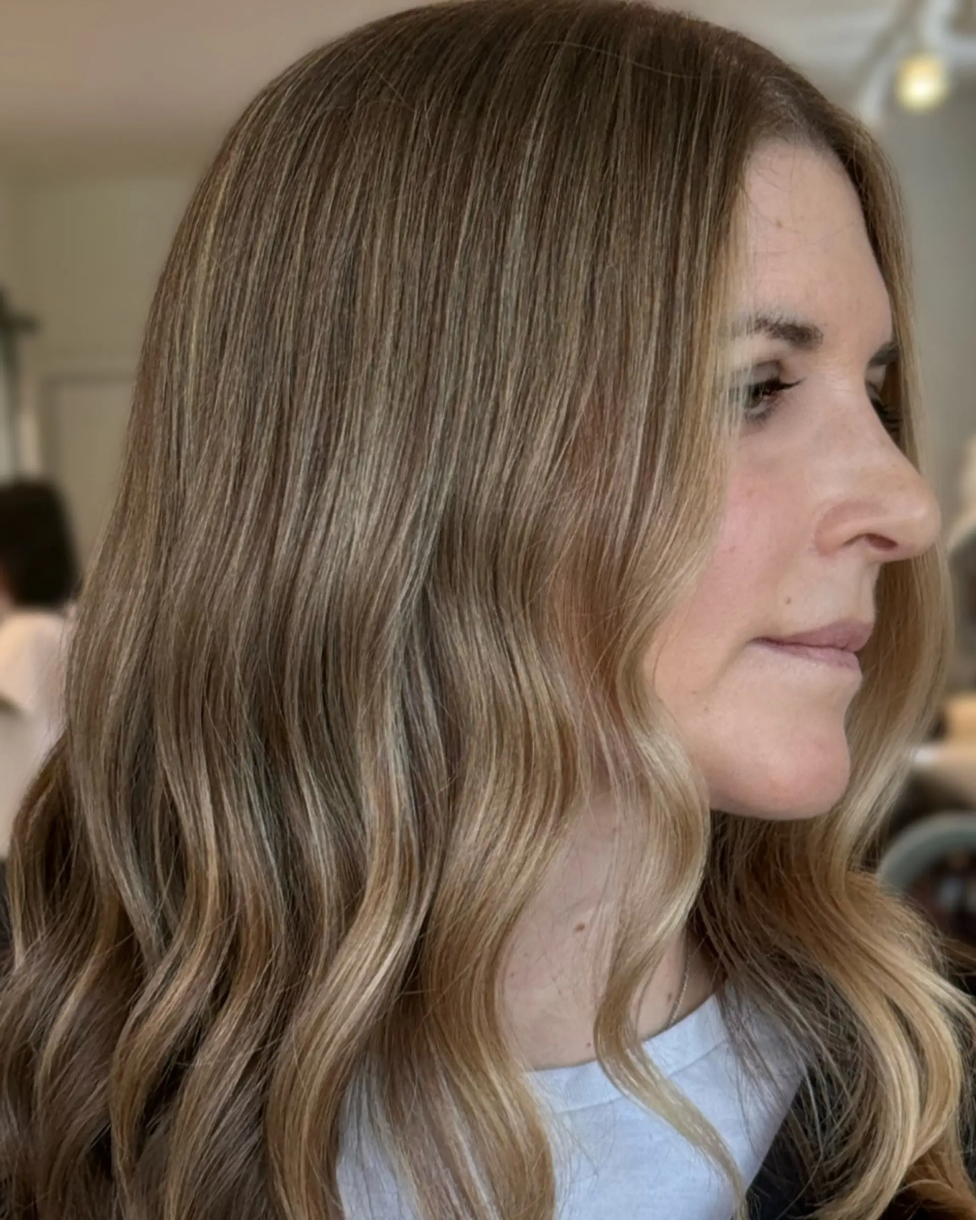Soft dimensional waves featuring subtle honey blonde highlights blended seamlessly over a light brown base. 1