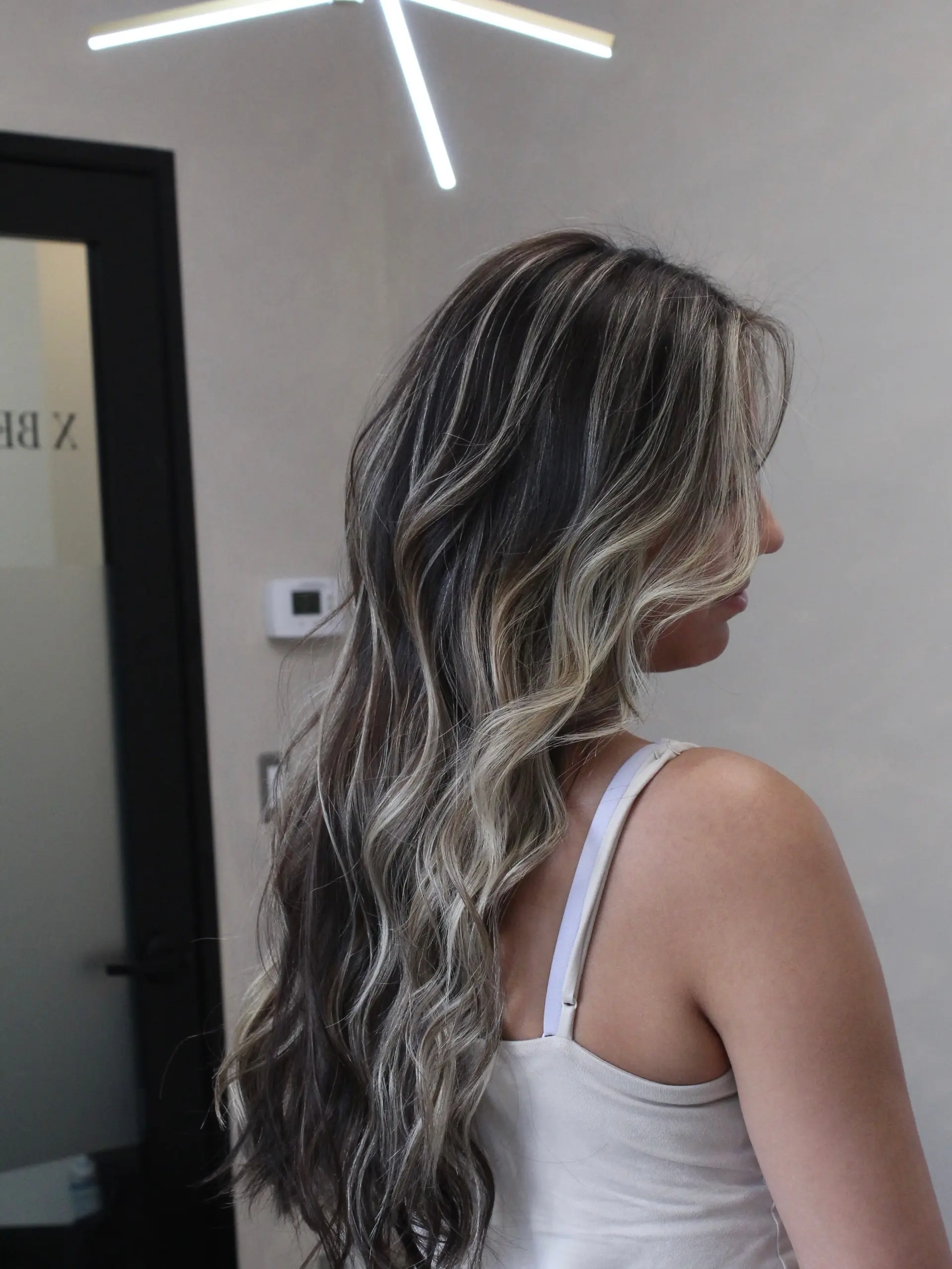 Long dark brown hair seamlessly blended with cool ash blonde highlights and styled in relaxed, voluminous waves. 1