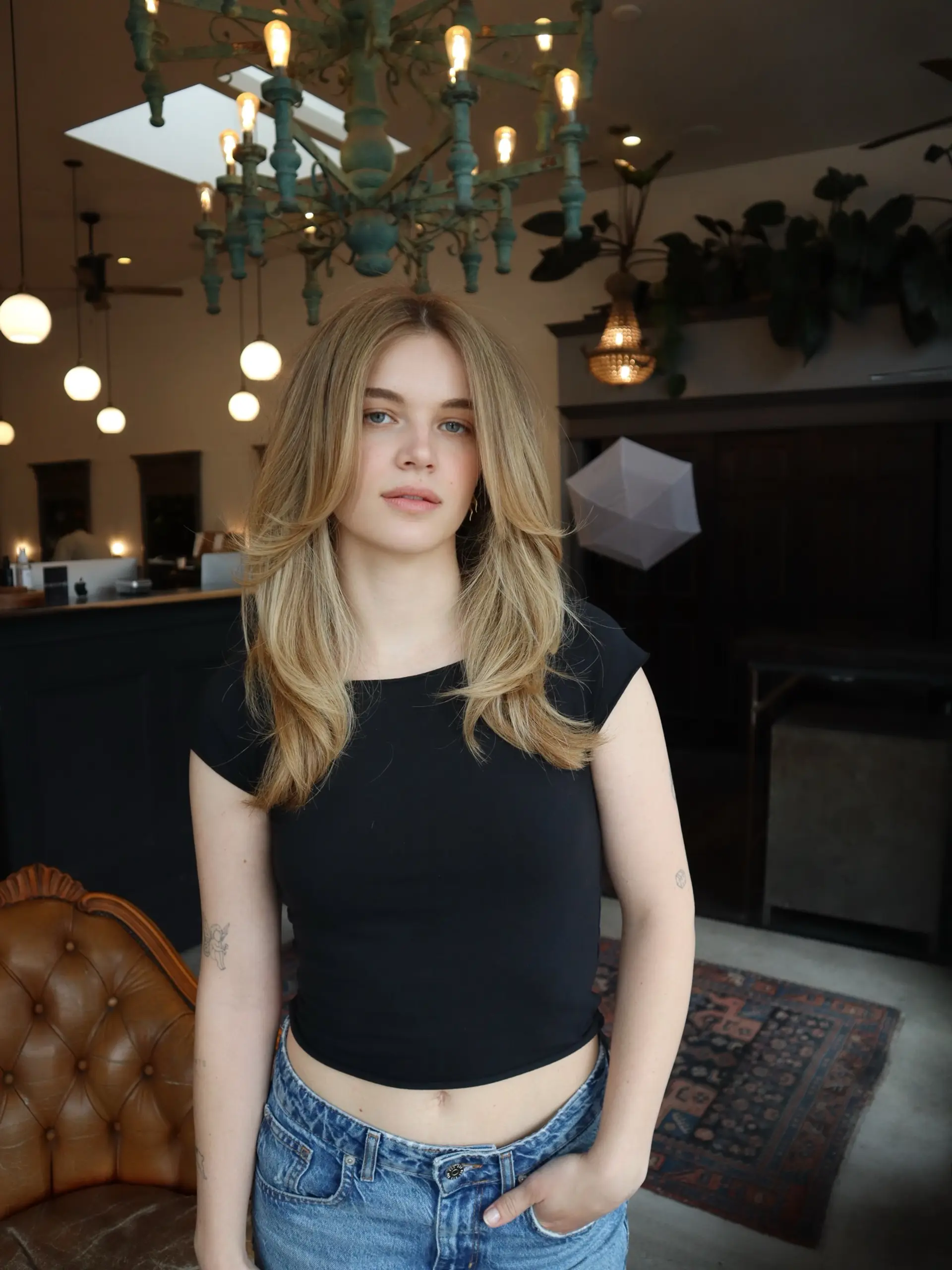 Long beige blonde hair cut with feathered face-framing layers and styled into a voluminous, soft blowout. 1