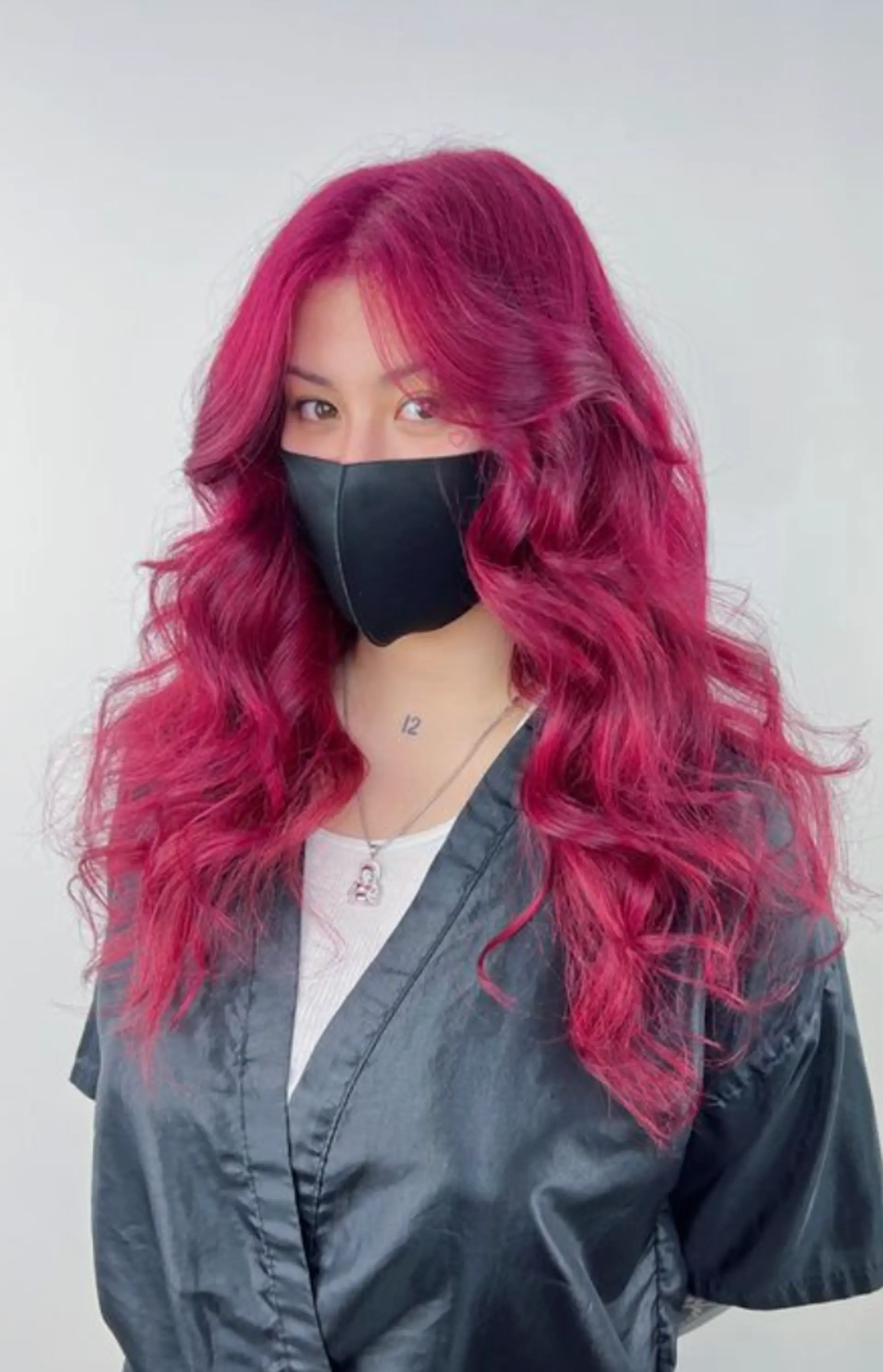The hairstyle features vibrant magenta waves cascading down to a long length, characterized by face-framing layers that enhance the wavy texture. 1