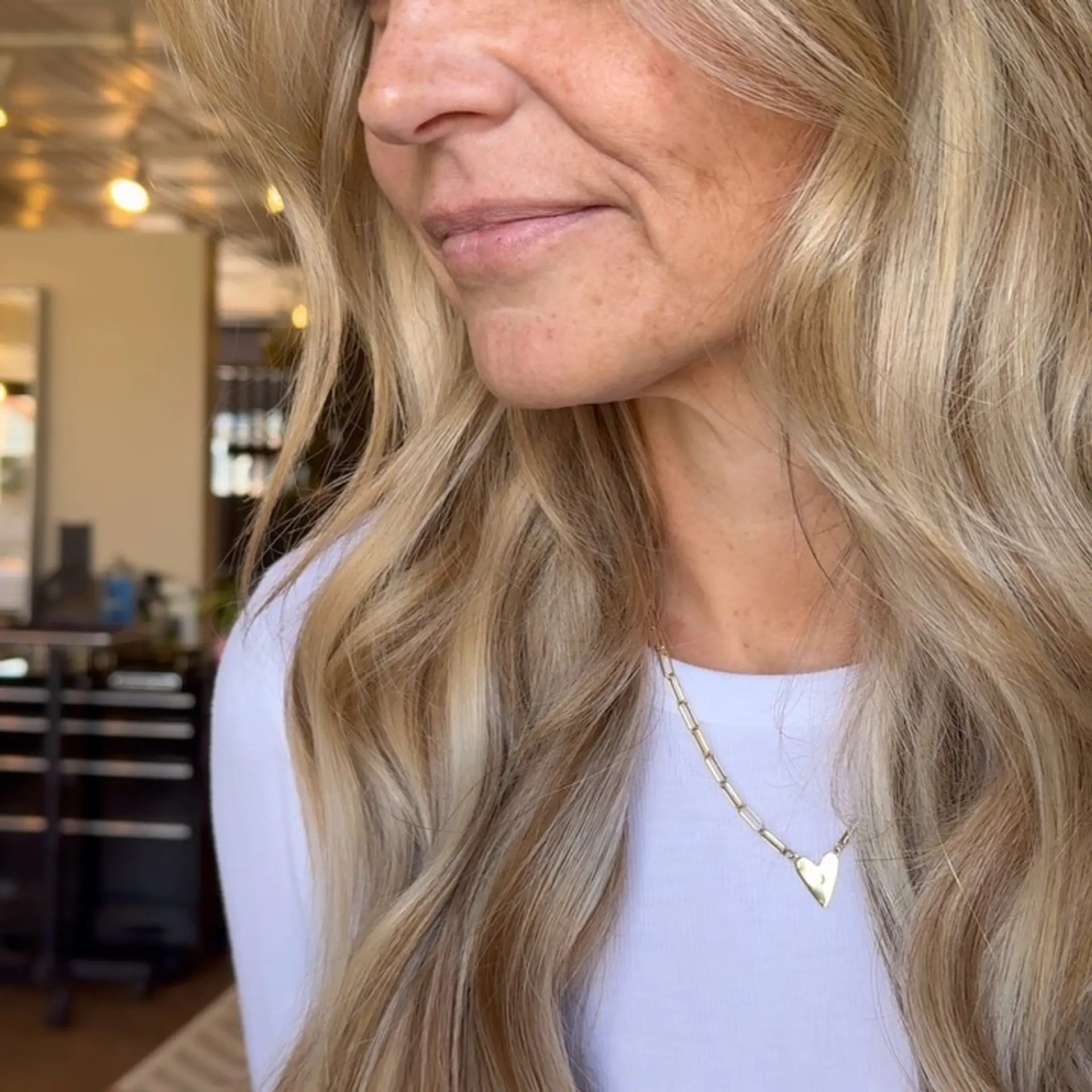 Long, dimensional blonde hair styled in soft, cascading waves seamlessly blended with weft extensions. 1